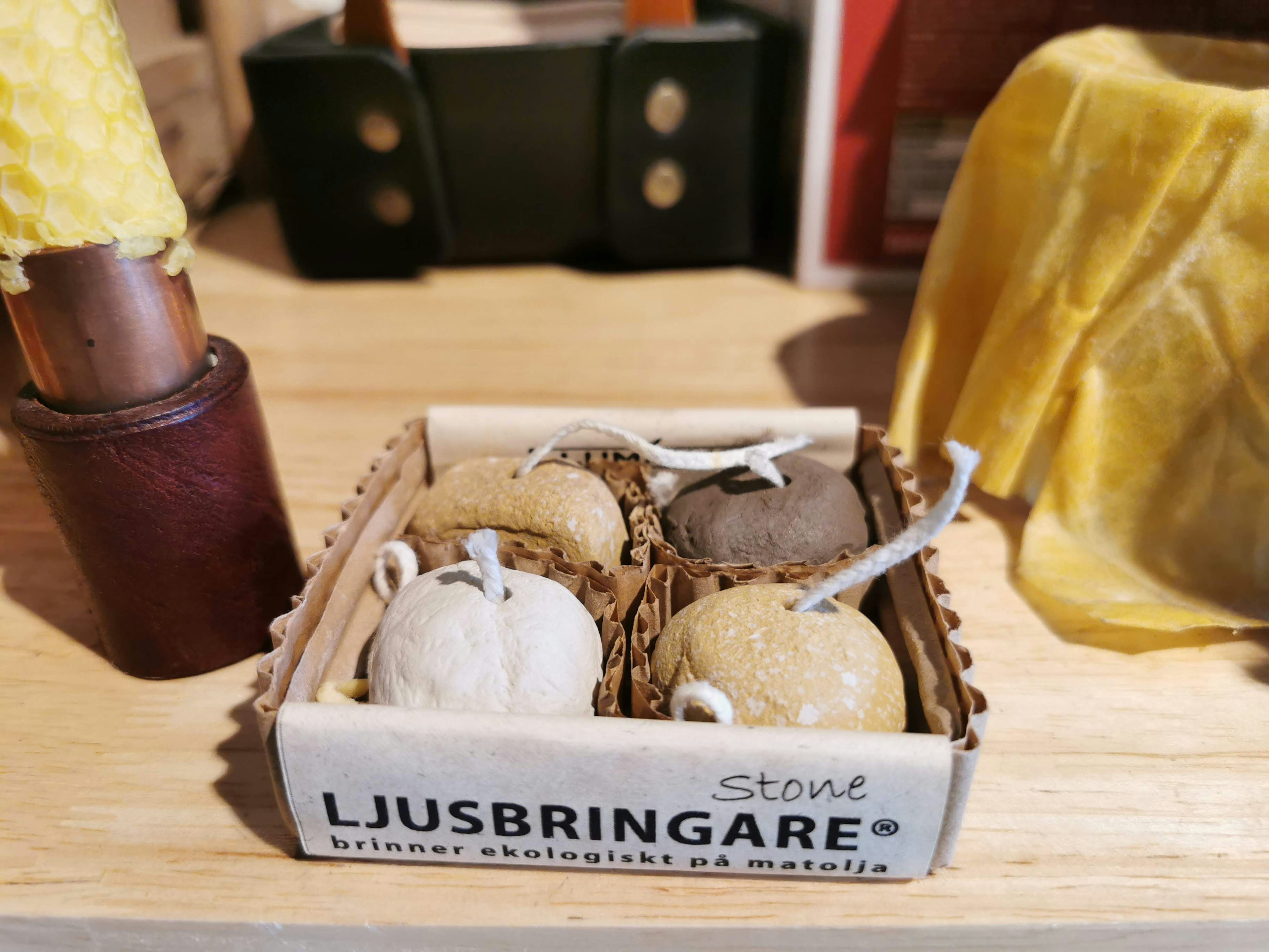 Set of four candles in a wooden box with decorative items in the background