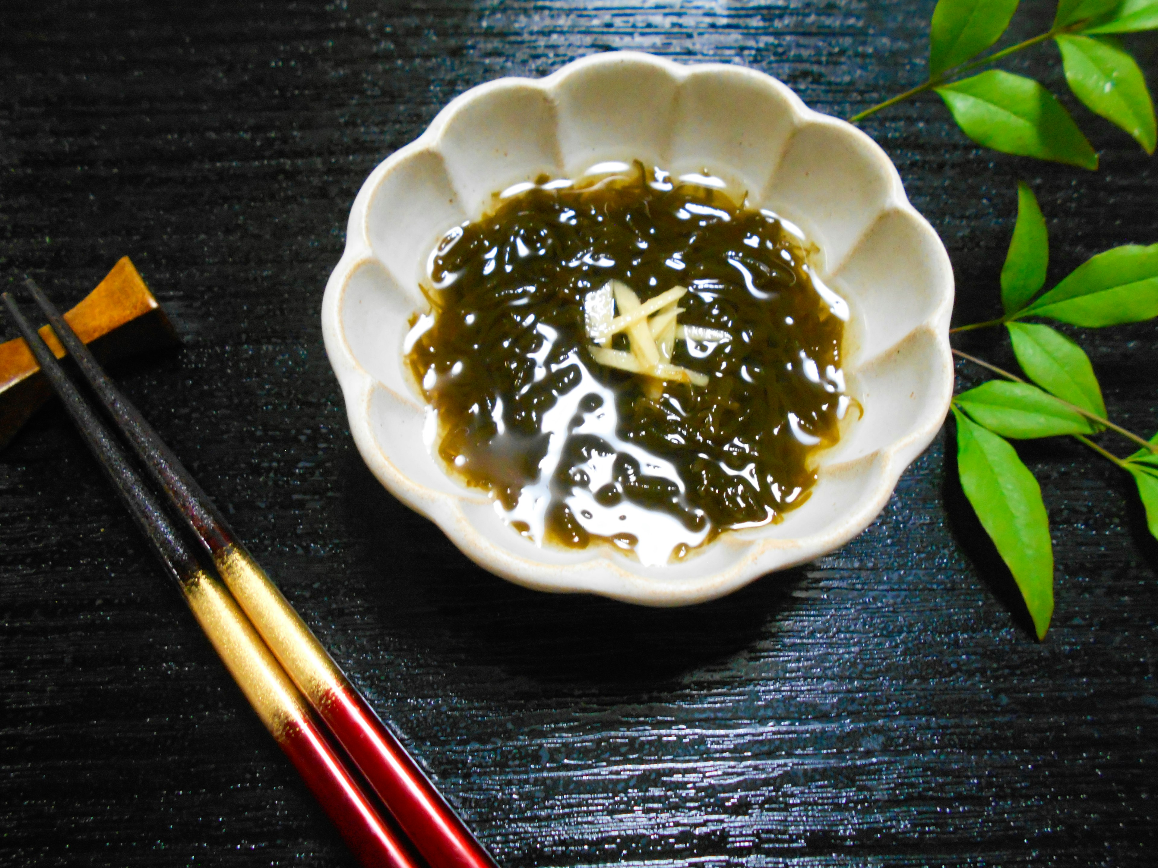 Seaweed salad in a white floral bowl with chopsticks beside it