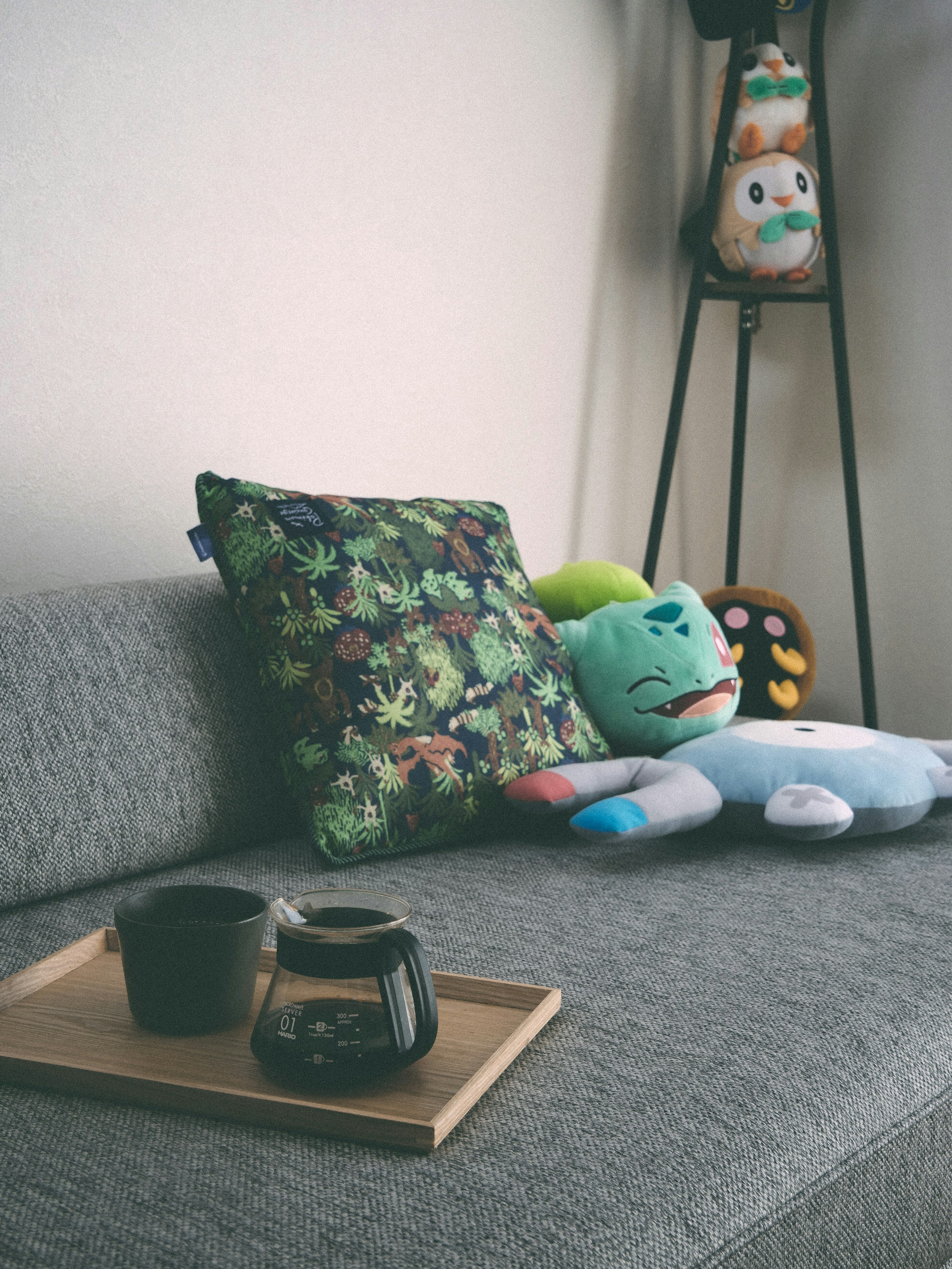 Modern sofa with a green plant-patterned pillow and colorful plush toys