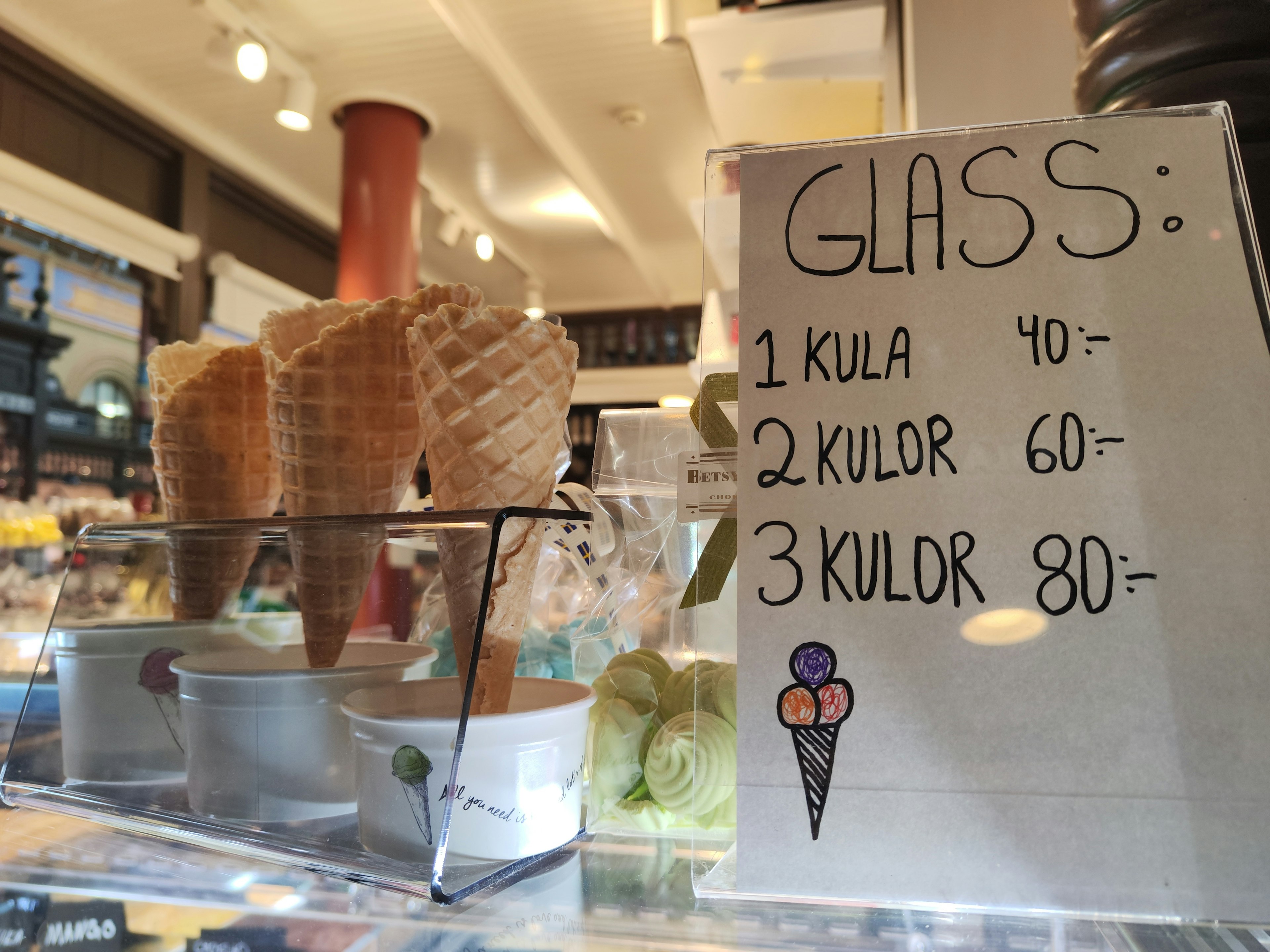 Une vitrine de cornets de glace avec une liste de prix pour différentes quantités