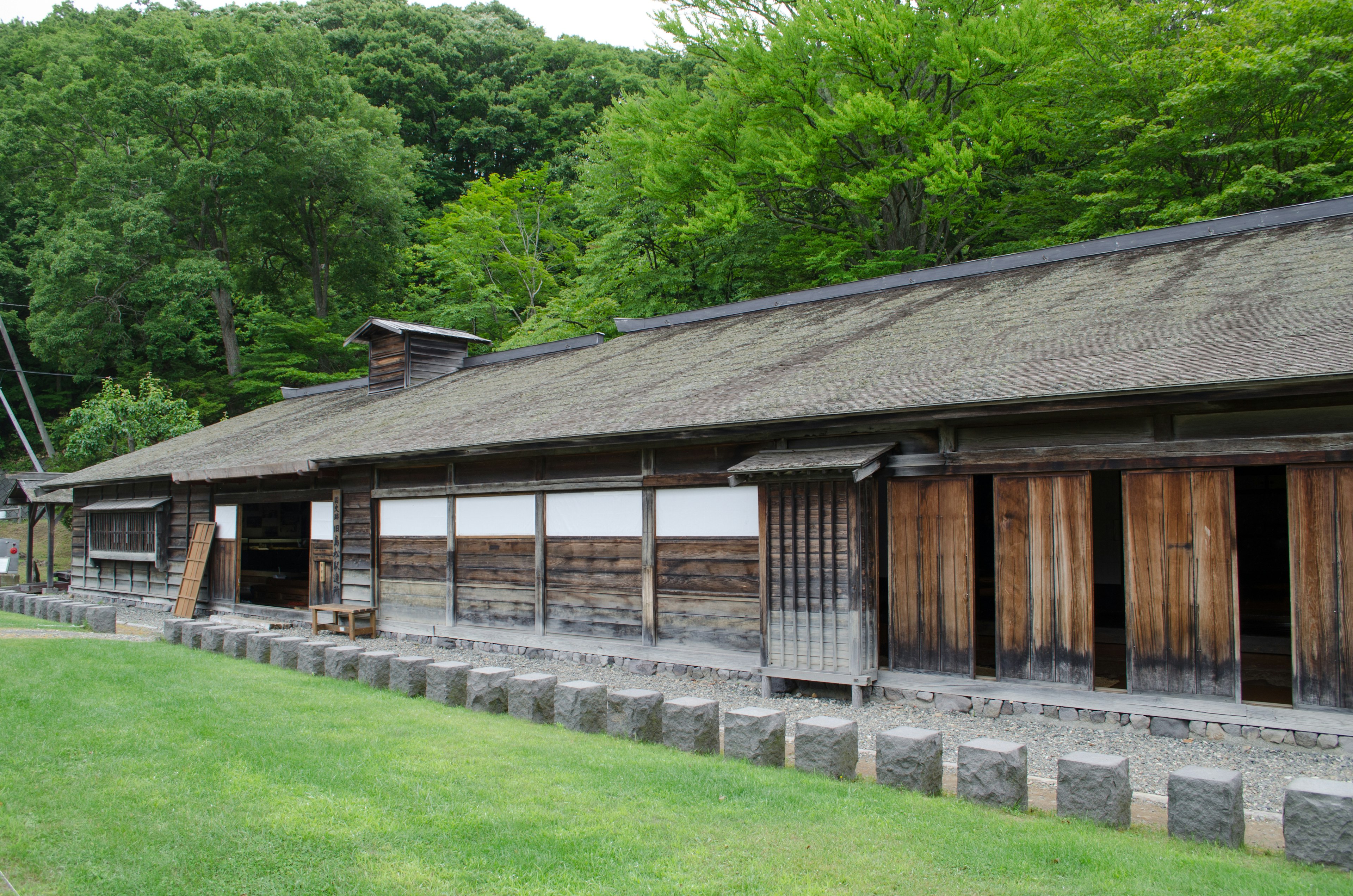 緑豊かな木々に囲まれた古い木造の建物の外観