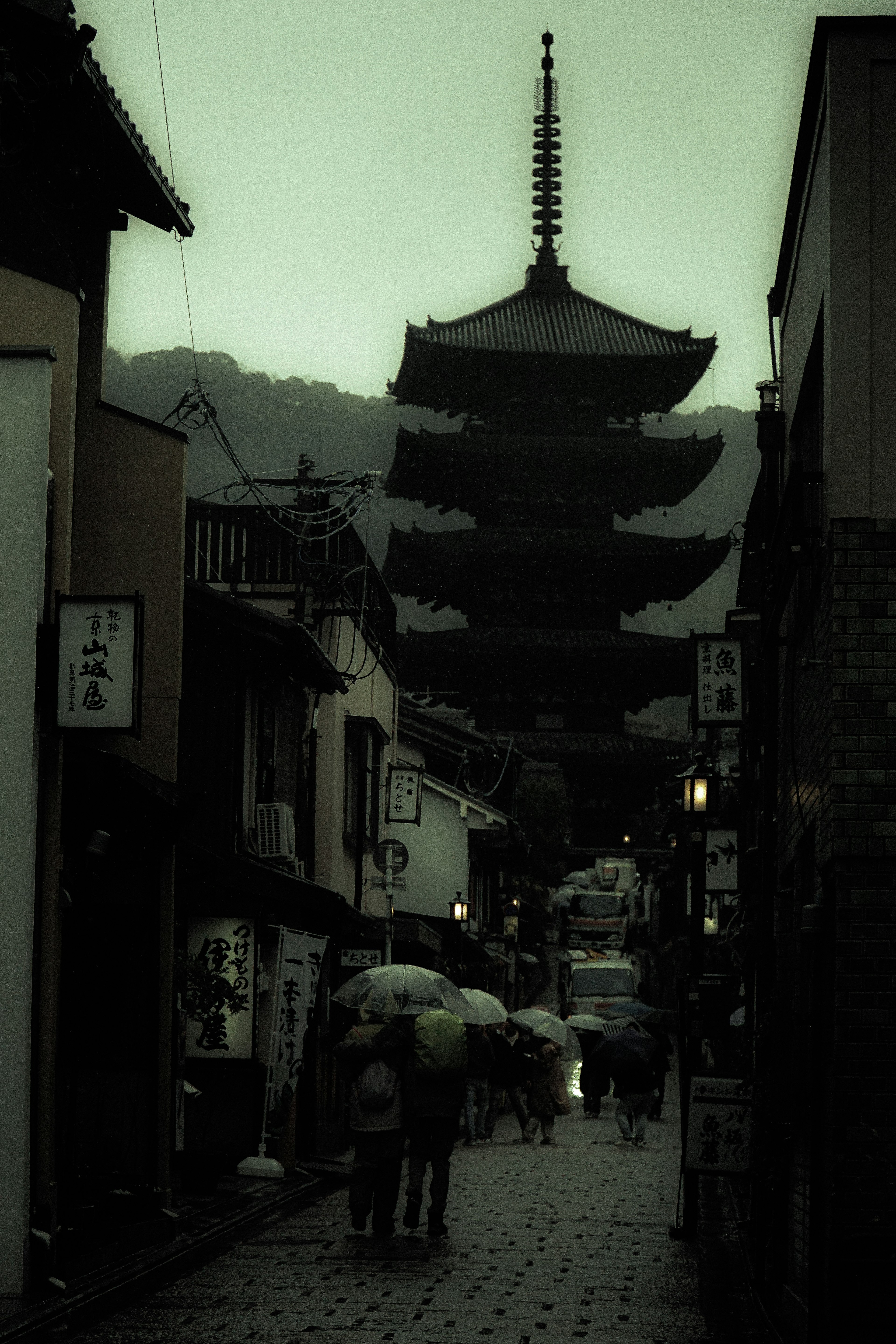 Silhouette d'une pagode et de personnes sous la pluie dans une rue de la ville