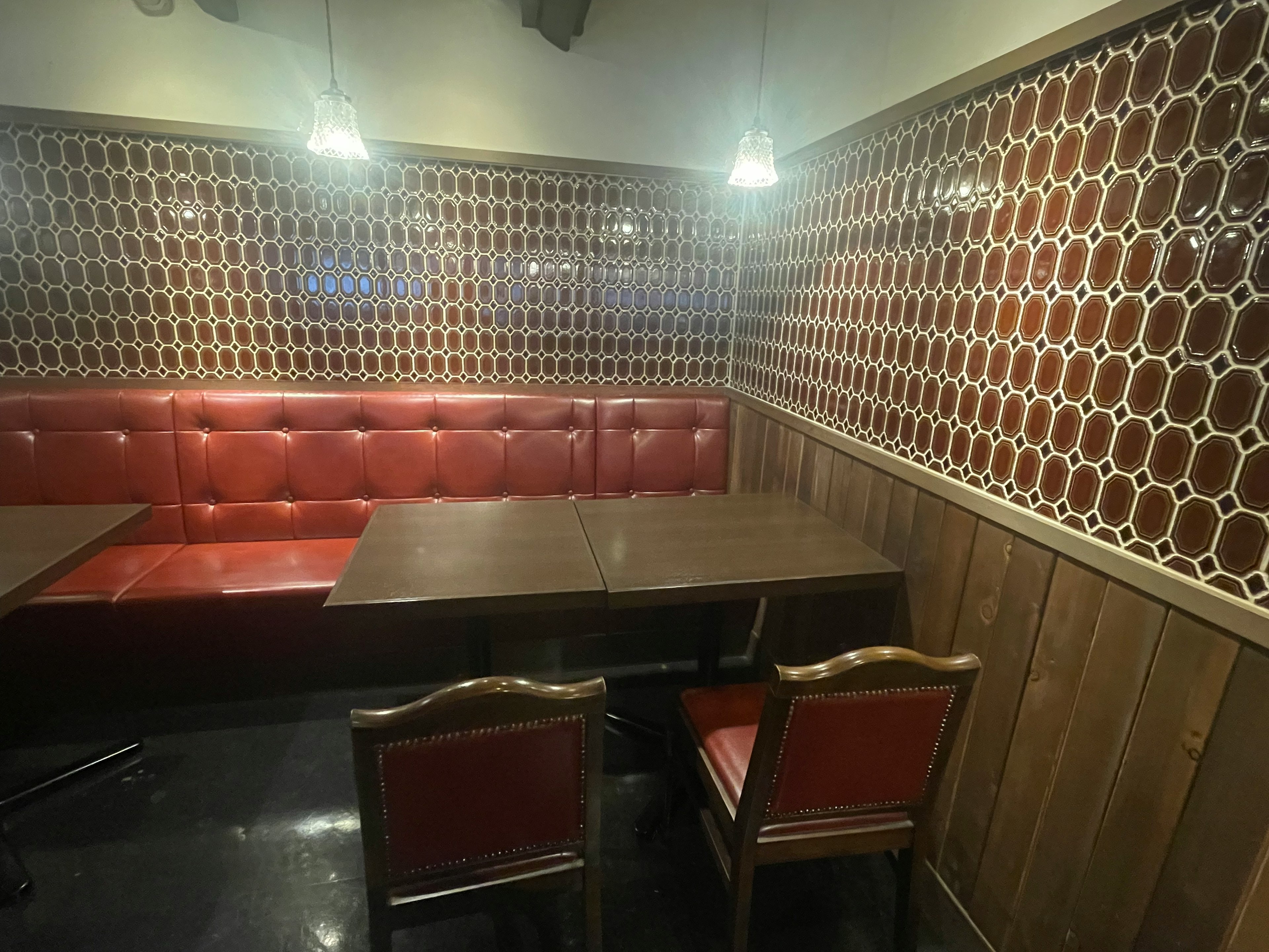 Interior de un restaurante con bancos de cuero rojo y mesas de madera