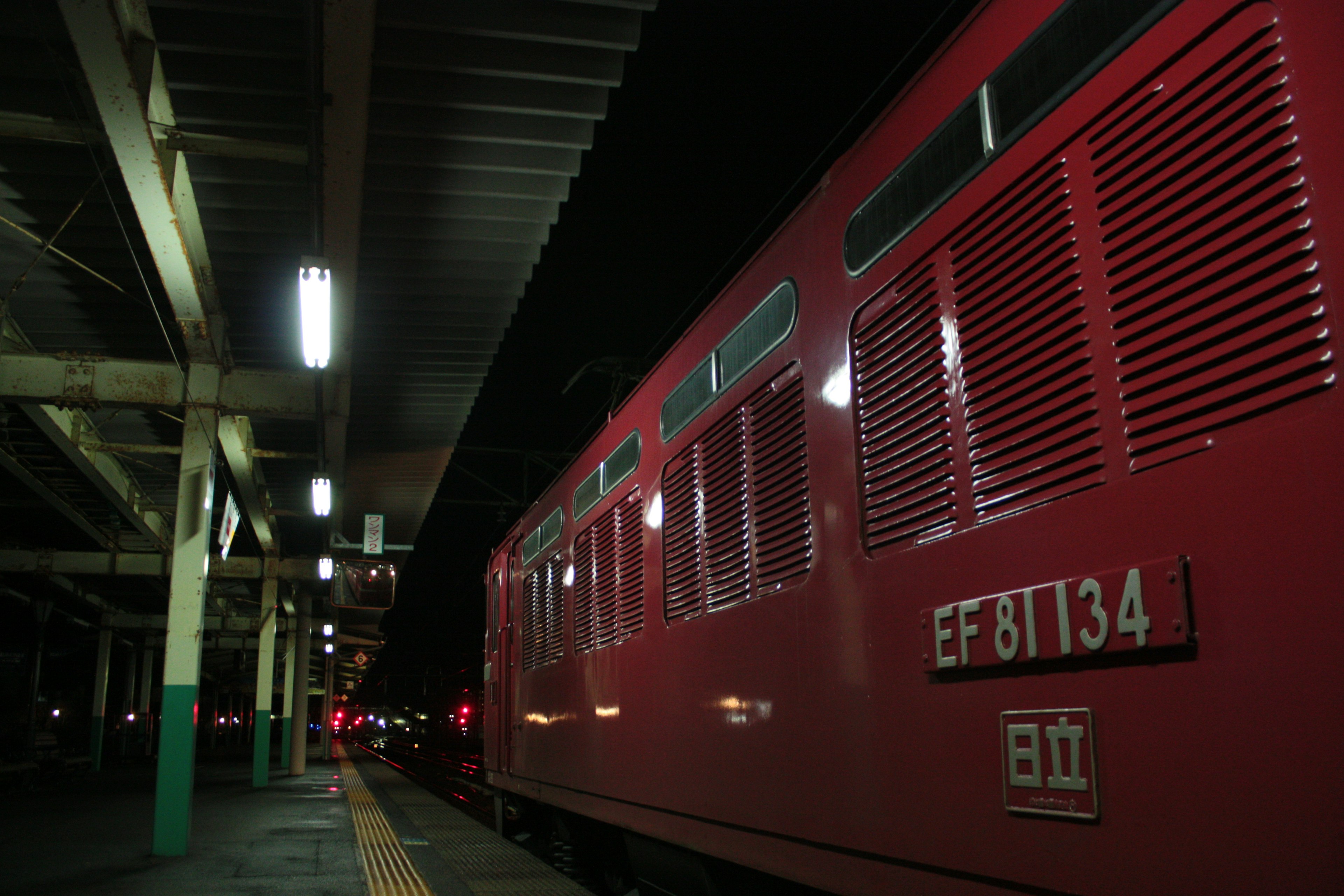 夜の駅に停車中の赤い列車と照明