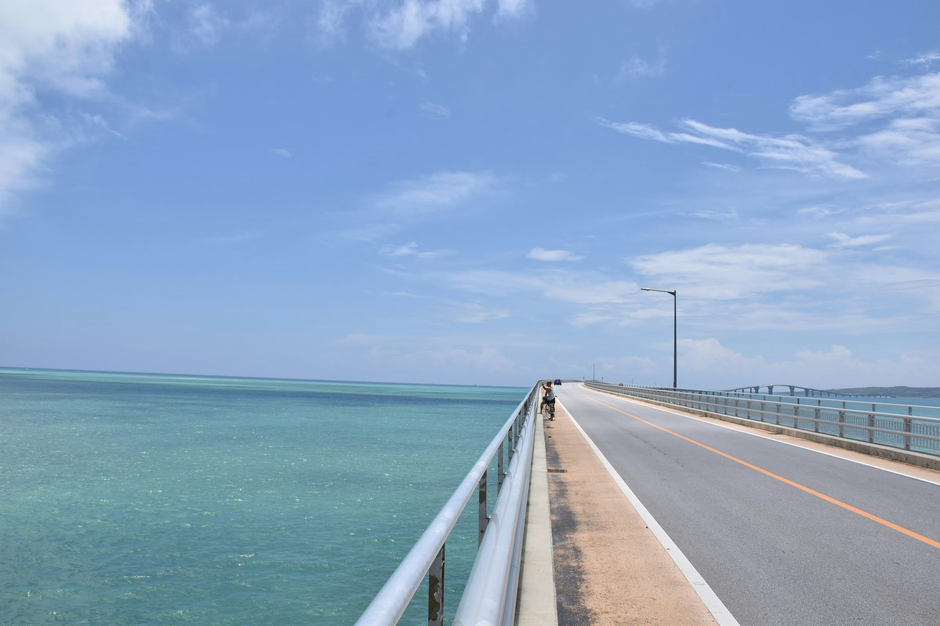 Panoramablick auf eine lange Brücke über türkisfarbenes Wasser unter einem klaren blauen Himmel