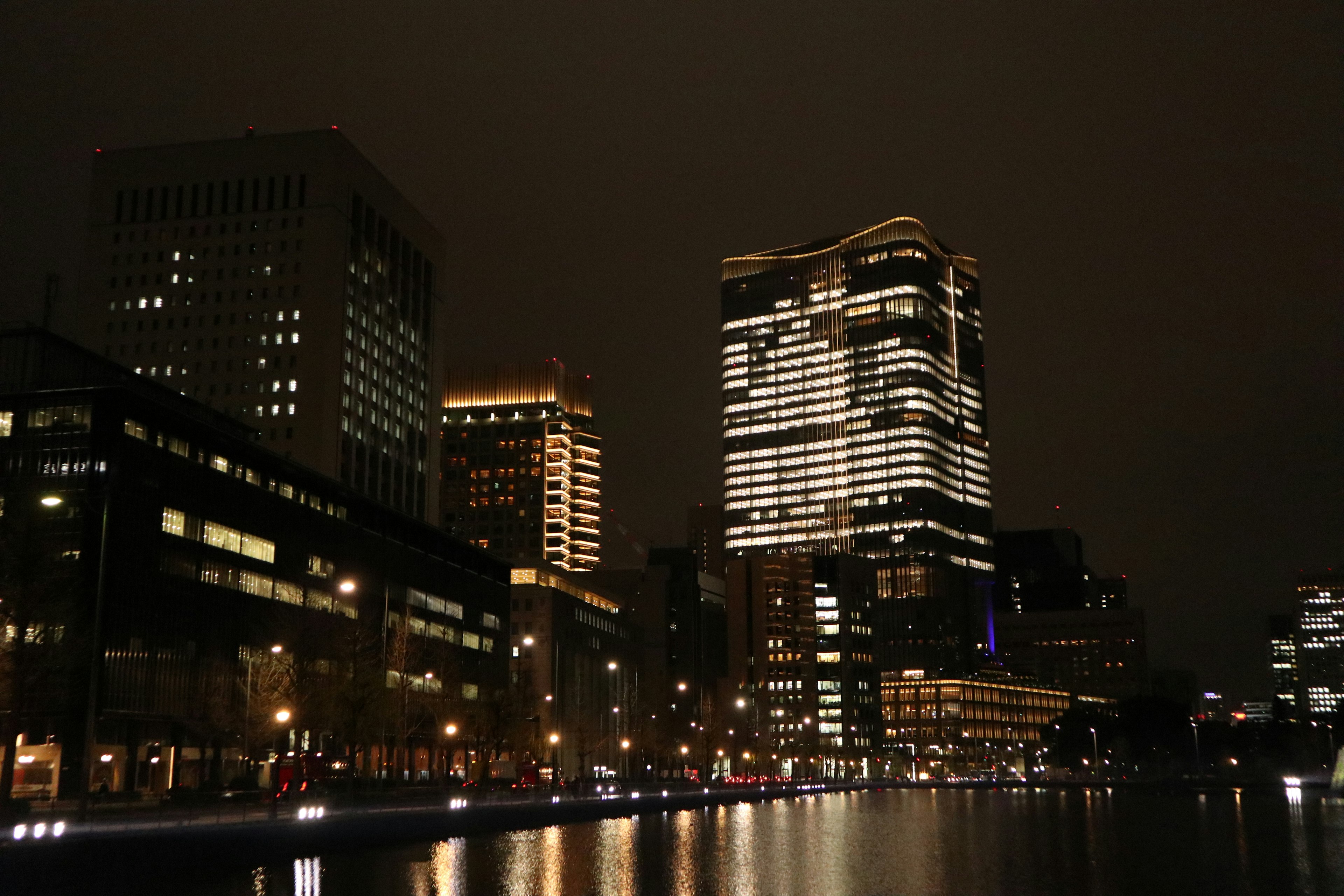 Night cityscape featuring skyscrapers and river reflections