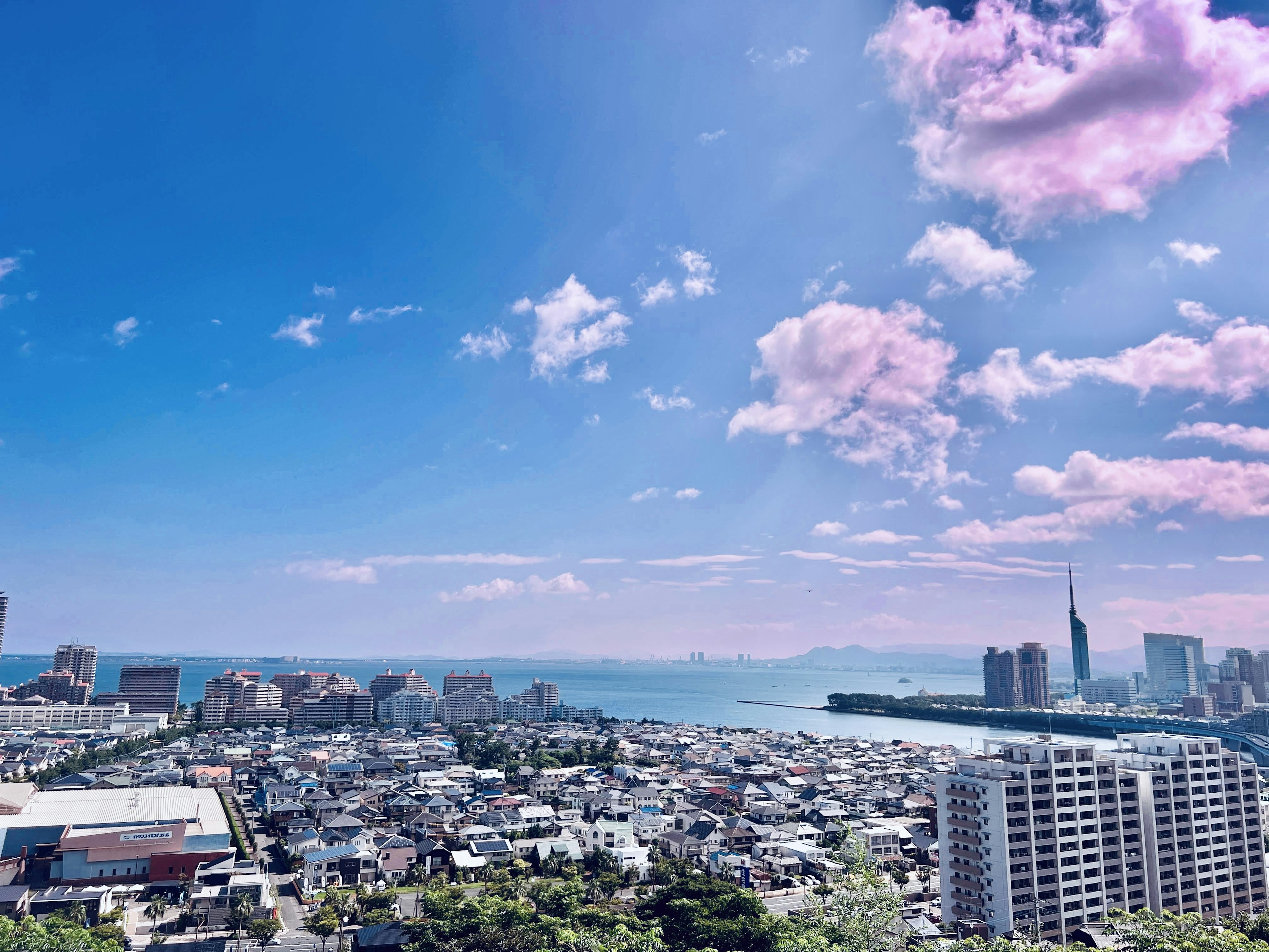 ท้องฟ้าสีฟ้าสดใสพร้อมเมฆ มีอาคารสูงและวิวทะเล