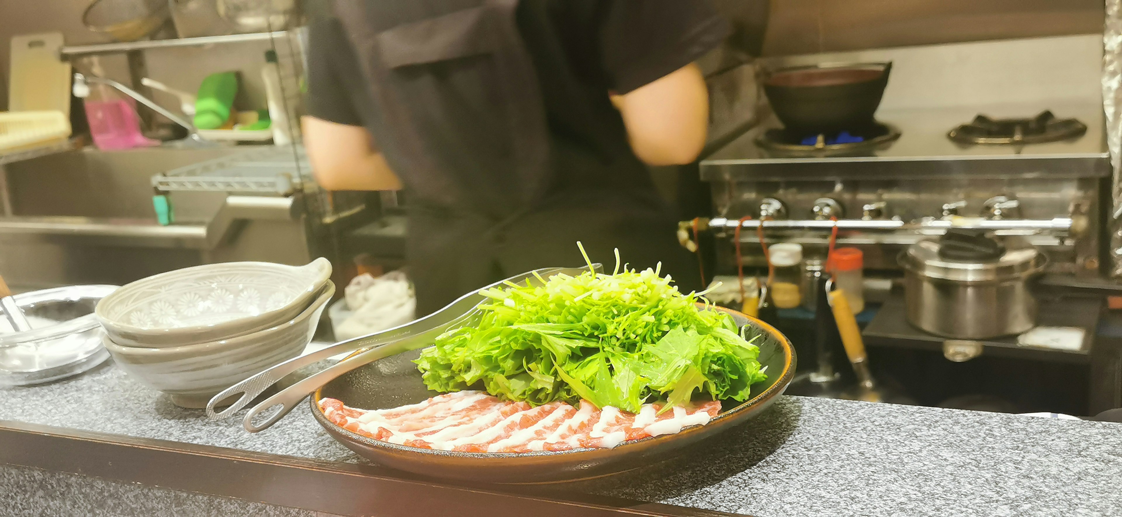 料理人がキッチンで肉と野菜を準備している様子