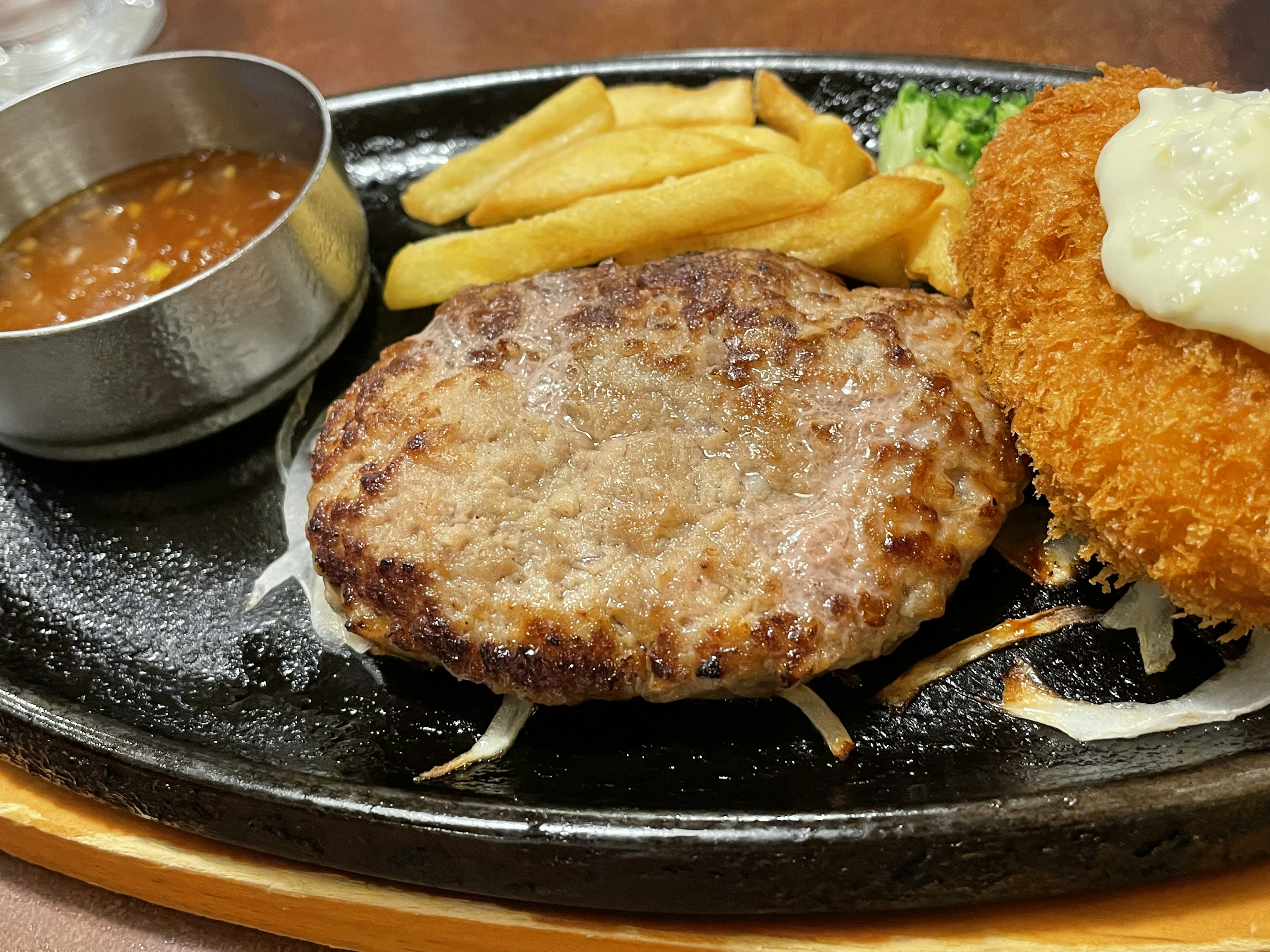 Piatto sfrigolante con hamburger succulento e crocchetta croccante servito con patatine e salsa