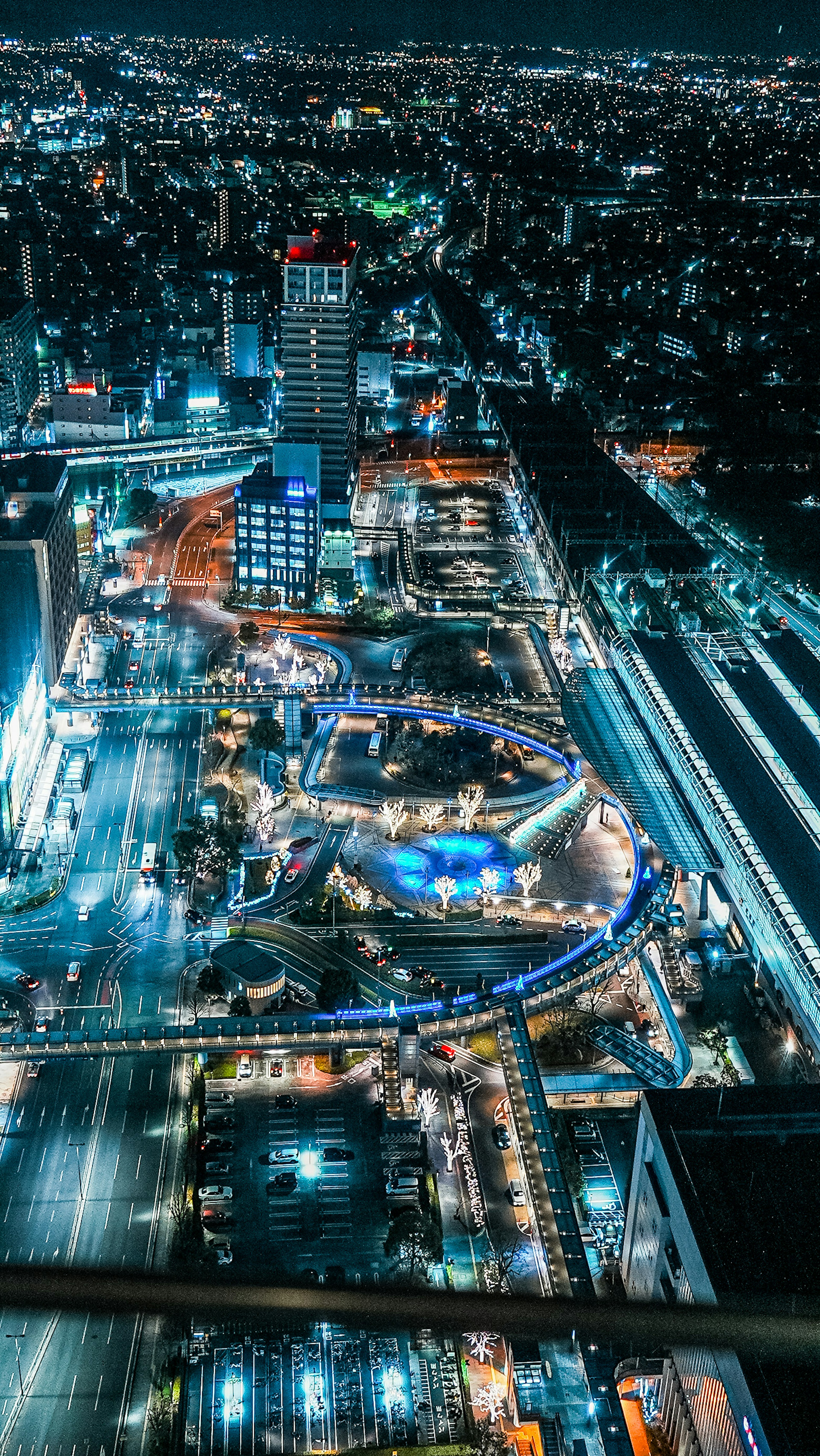 Vista aérea de un paisaje urbano vibrante de noche con edificios iluminados y carreteras transitadas