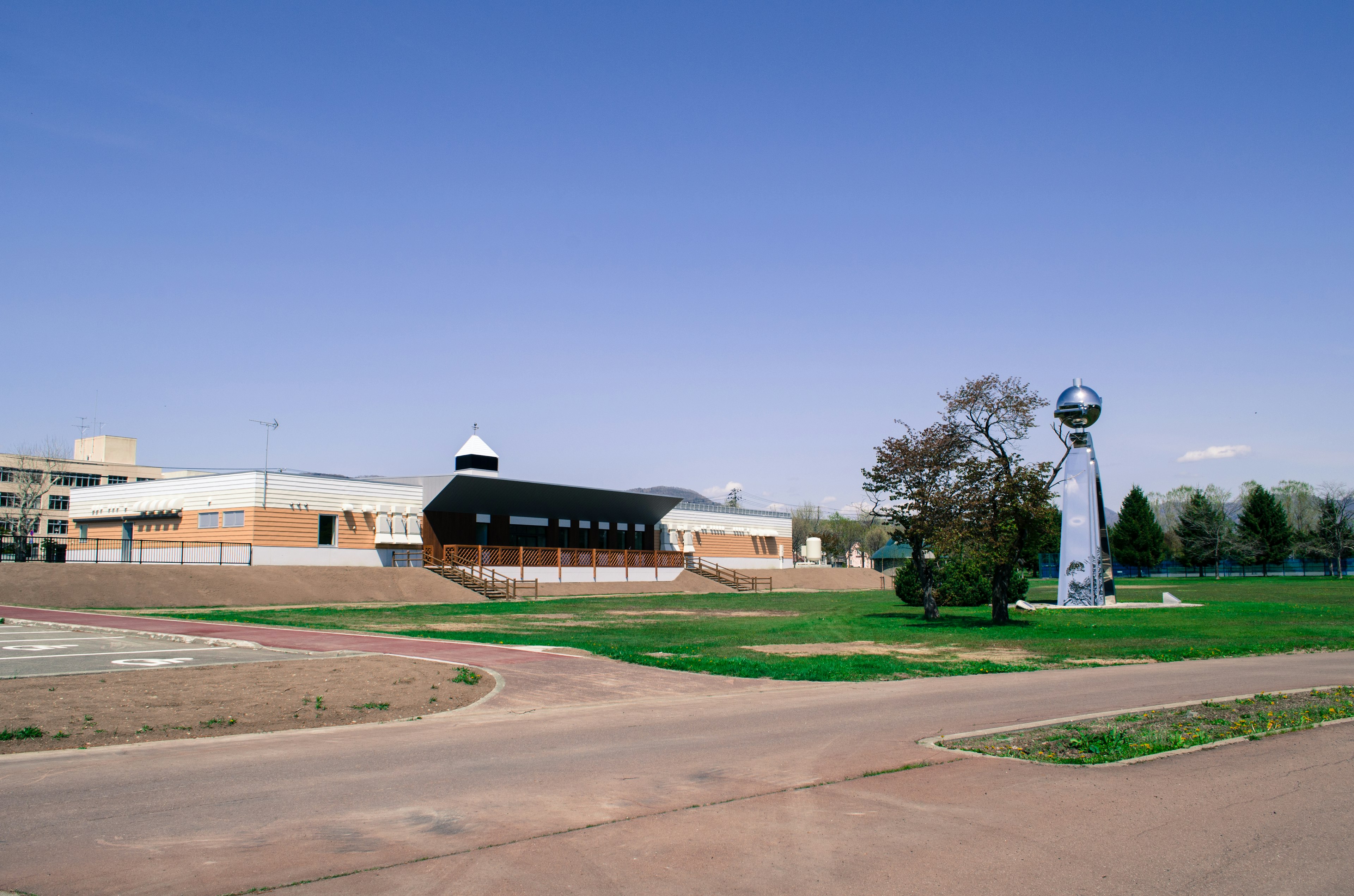 Modern building surrounded by green space with a prominent sculpture