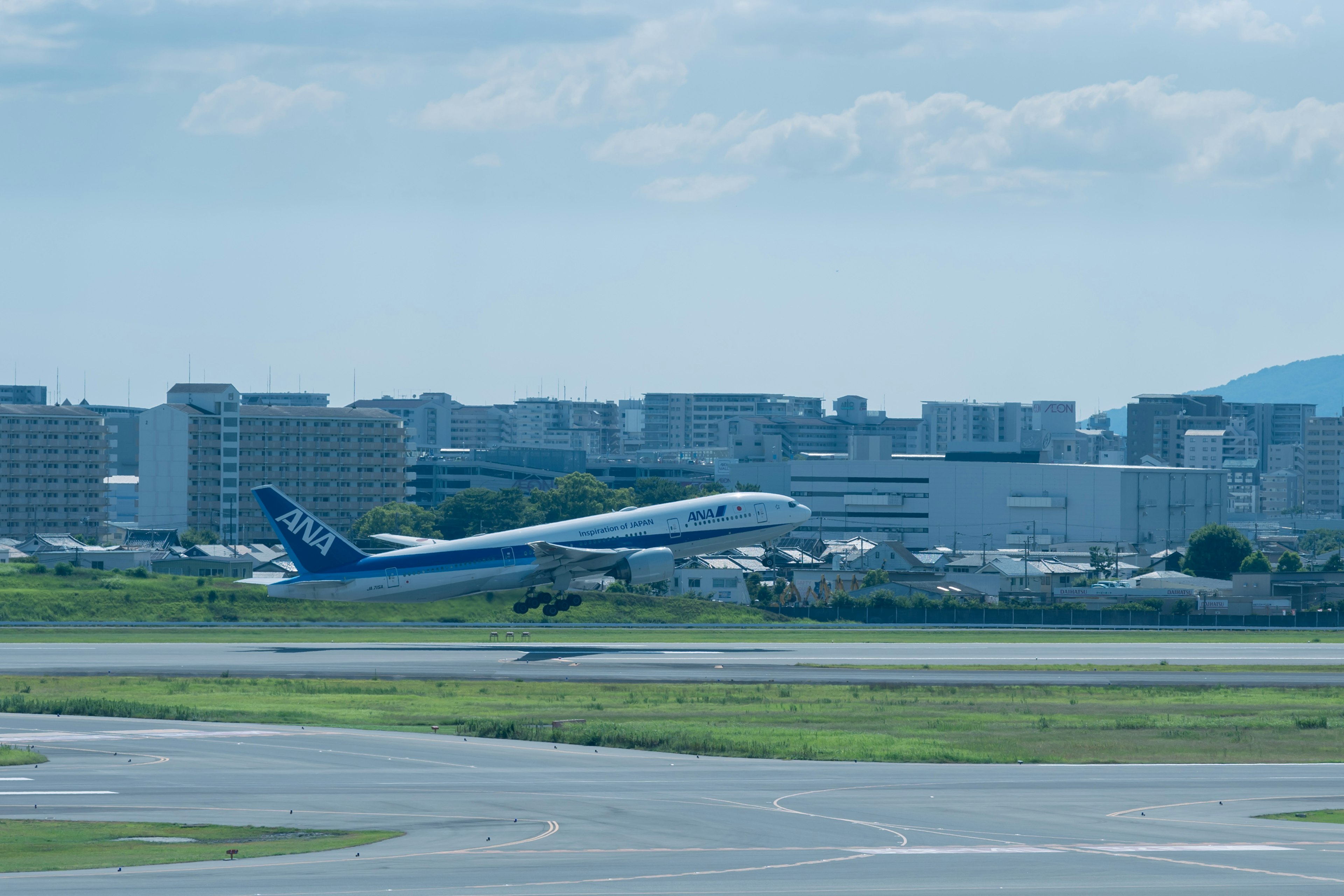 Aereo che decolla dalla pista con uno skyline urbano sotto un cielo blu