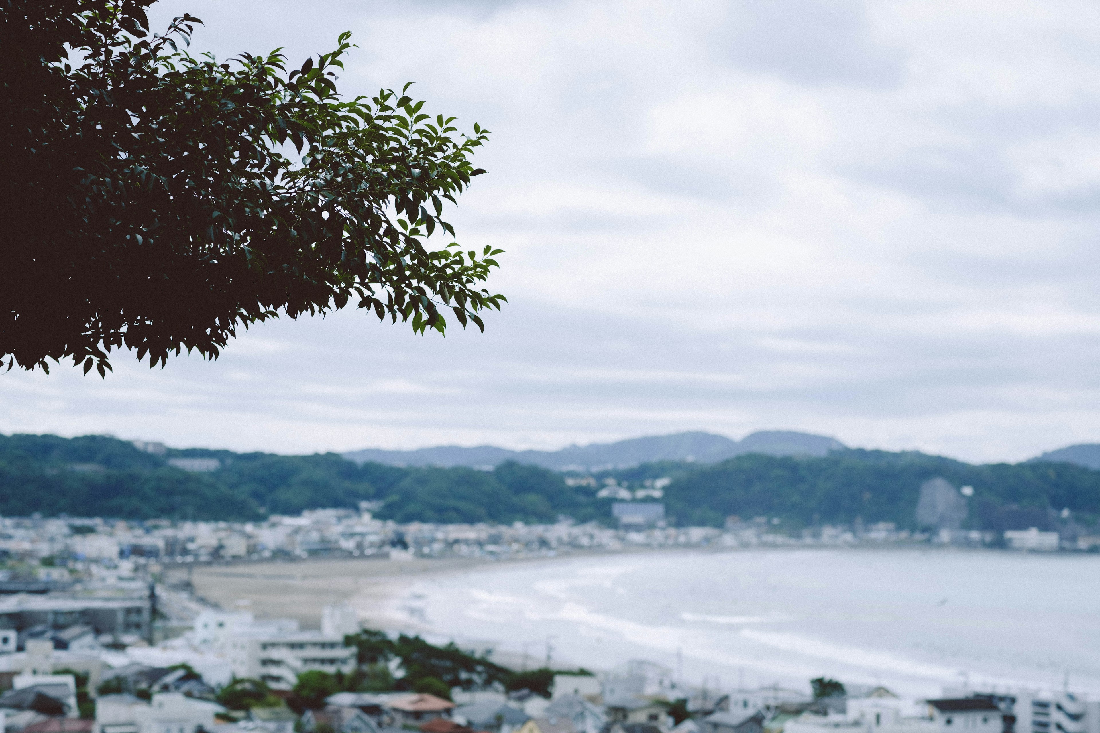 Coastal city view with cloudy sky and distant mountains