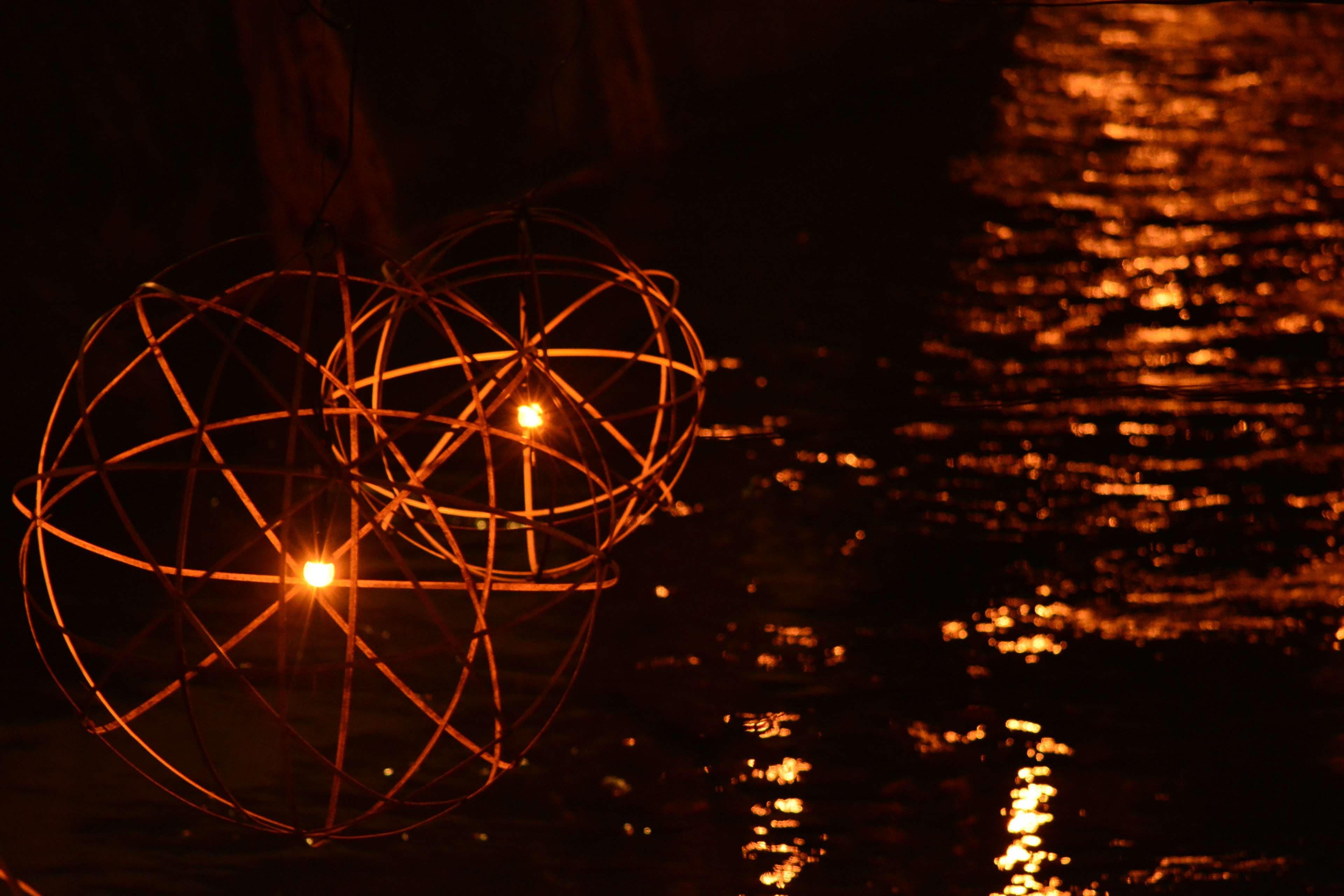 Oggetti sferici illuminati che galleggiano sull'acqua con illuminazione arancione