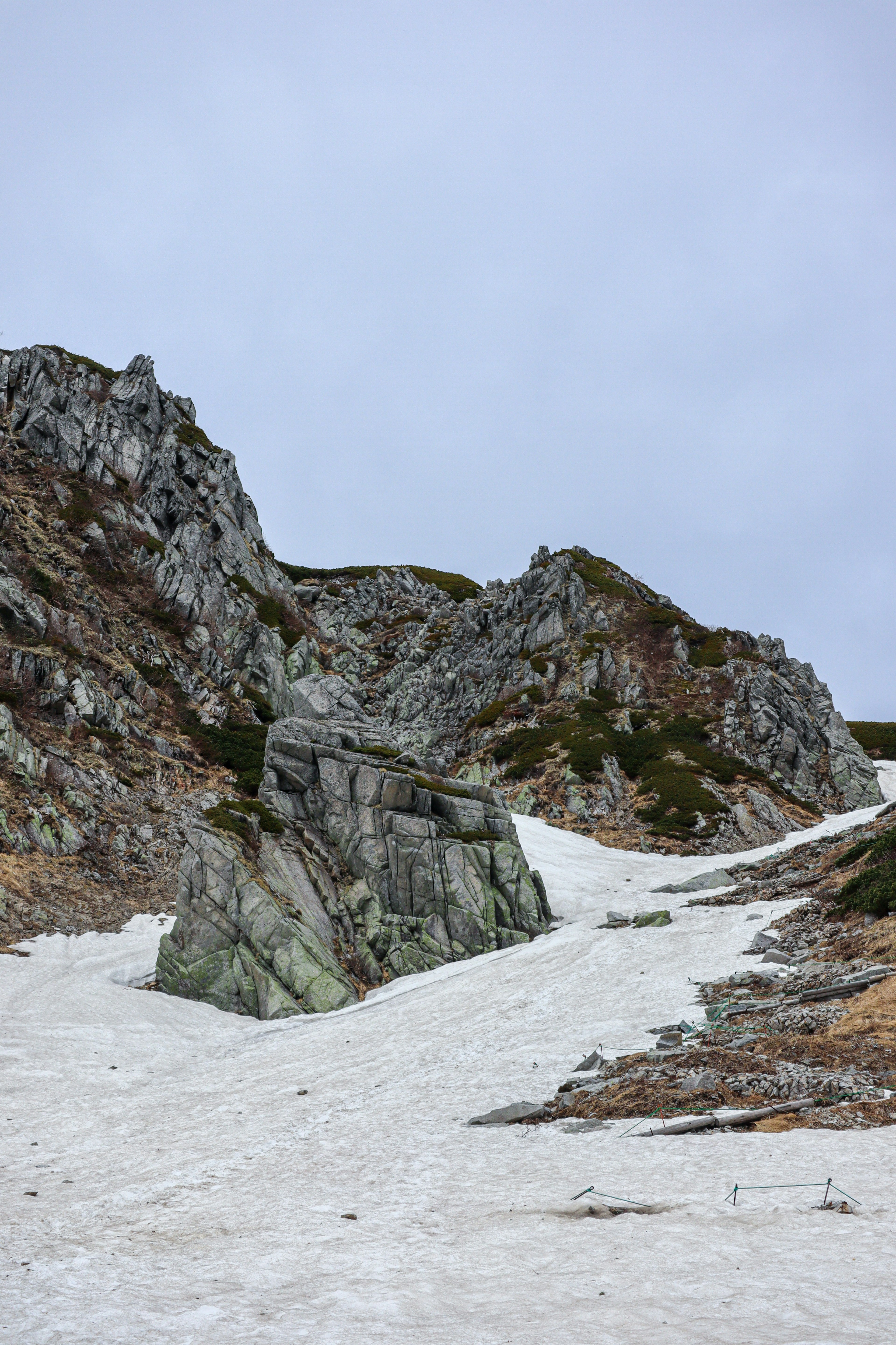 Pente rocheuse couverte de neige sous un ciel nuageux