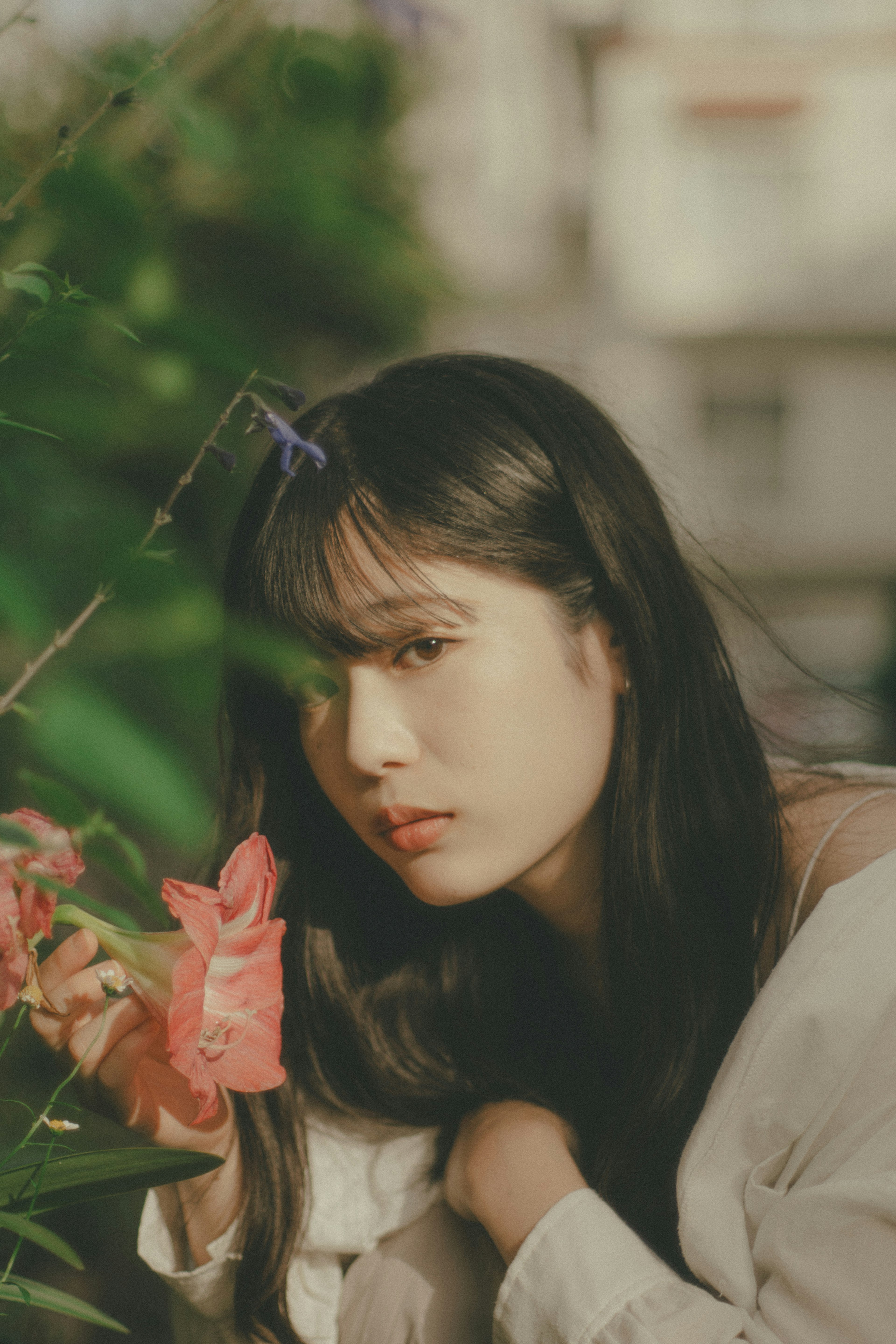 Une jeune femme posant près de fleurs colorées sous un doux soleil