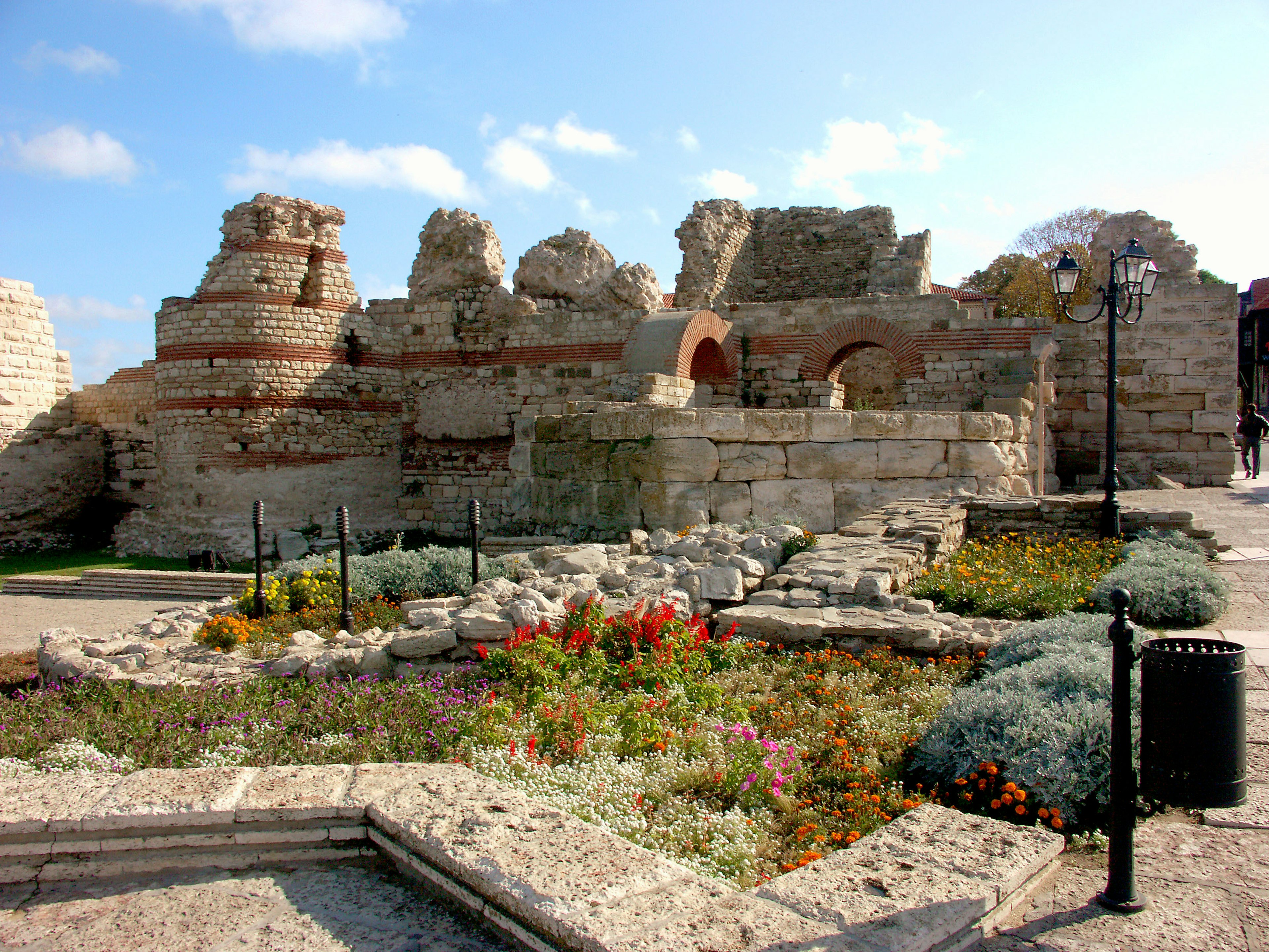 Ancient ruins surrounded by colorful flowers in a park setting