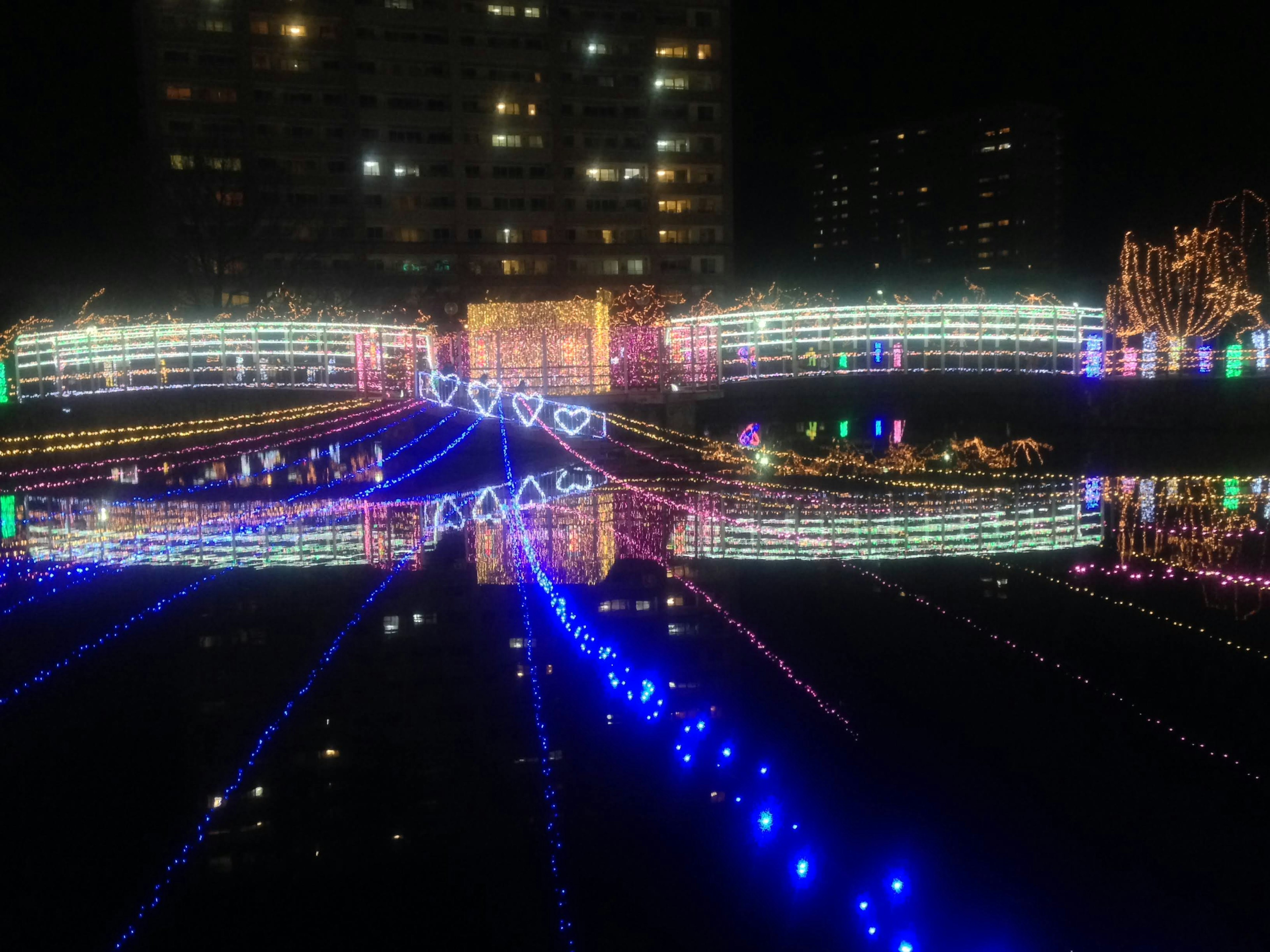 Puente decorado con luces coloridas reflejándose en el agua por la noche