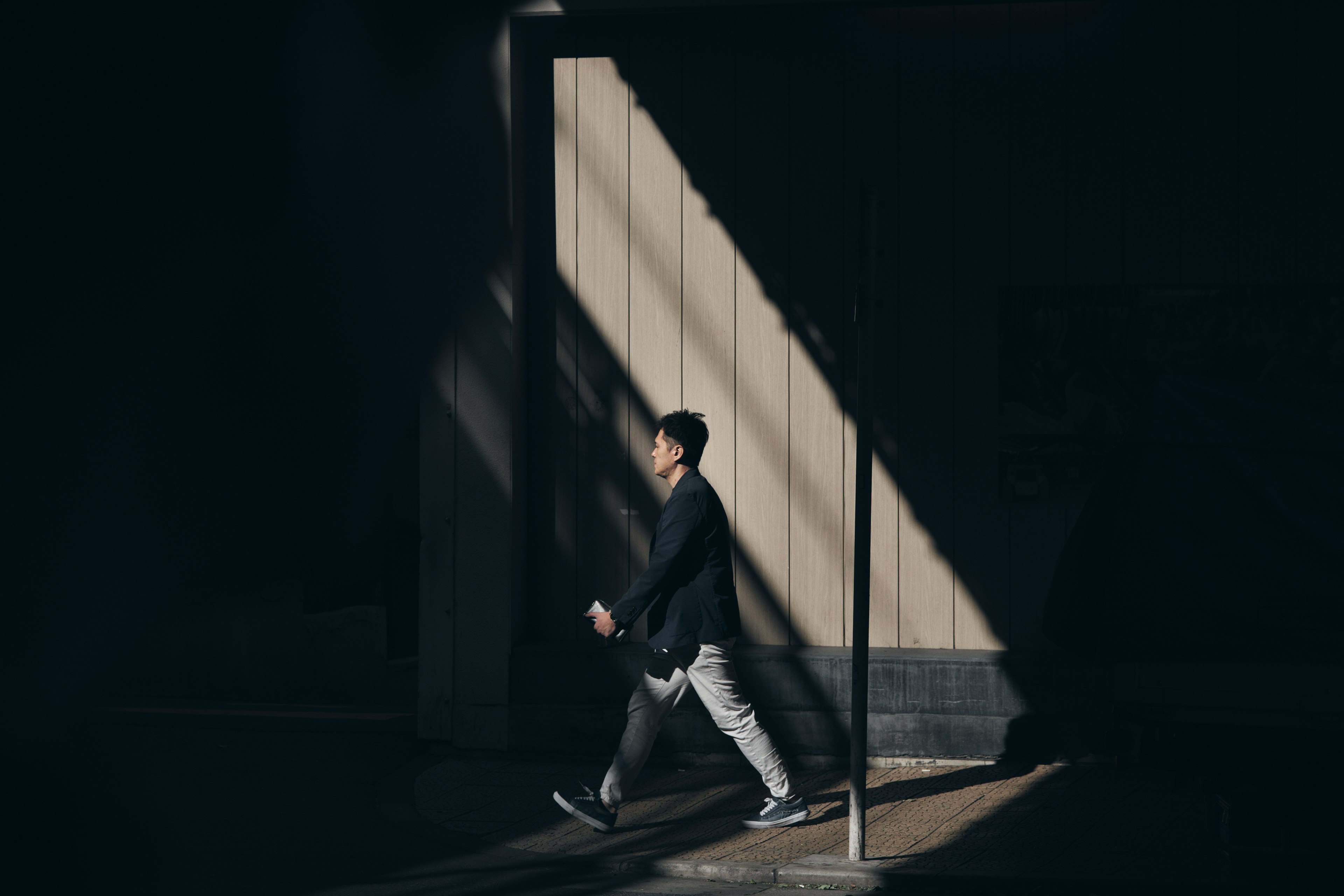 Silhouette d'un homme marchant à travers des ombres avec des rayures de lumière