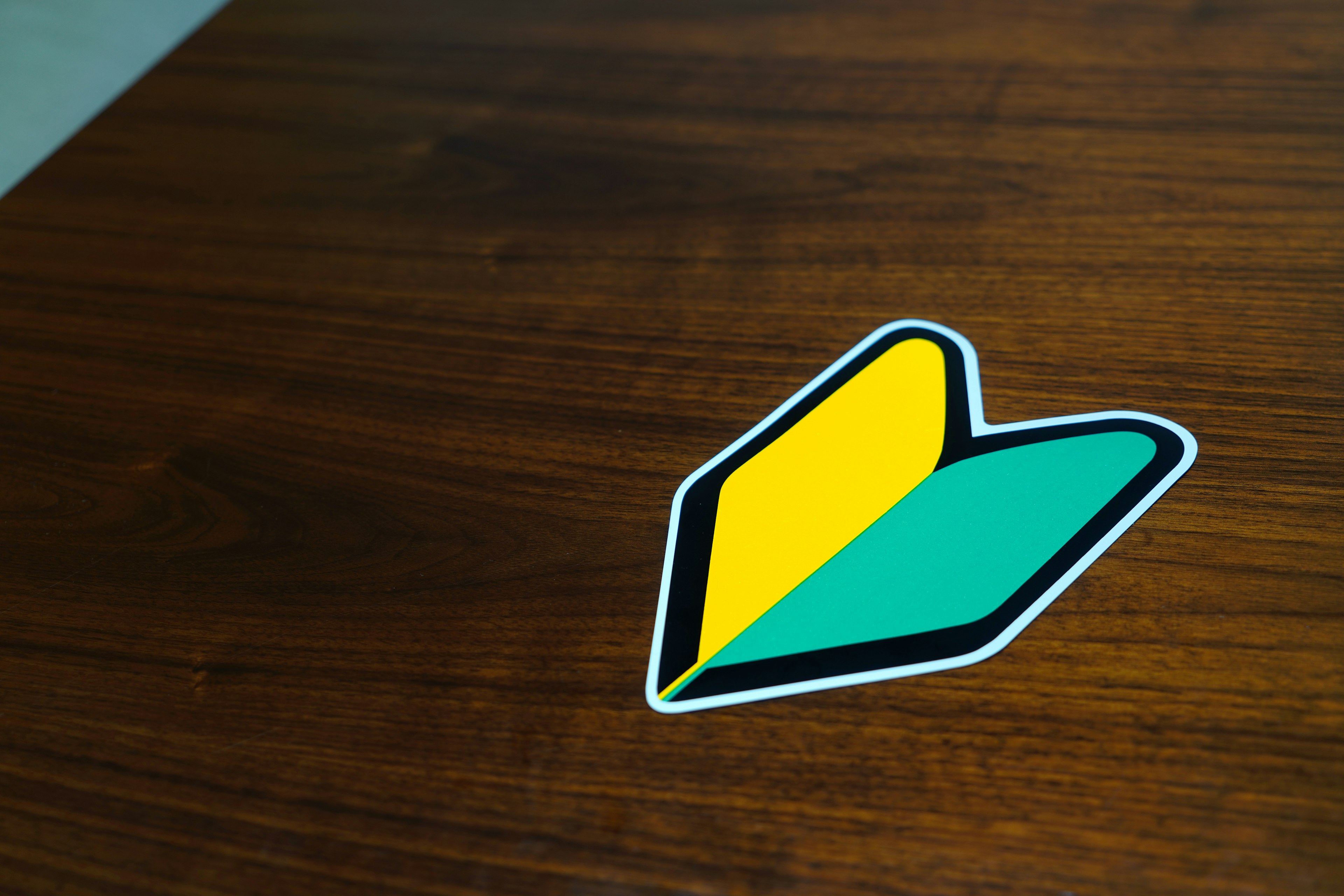 A green and yellow heart-shaped sticker on a wooden table