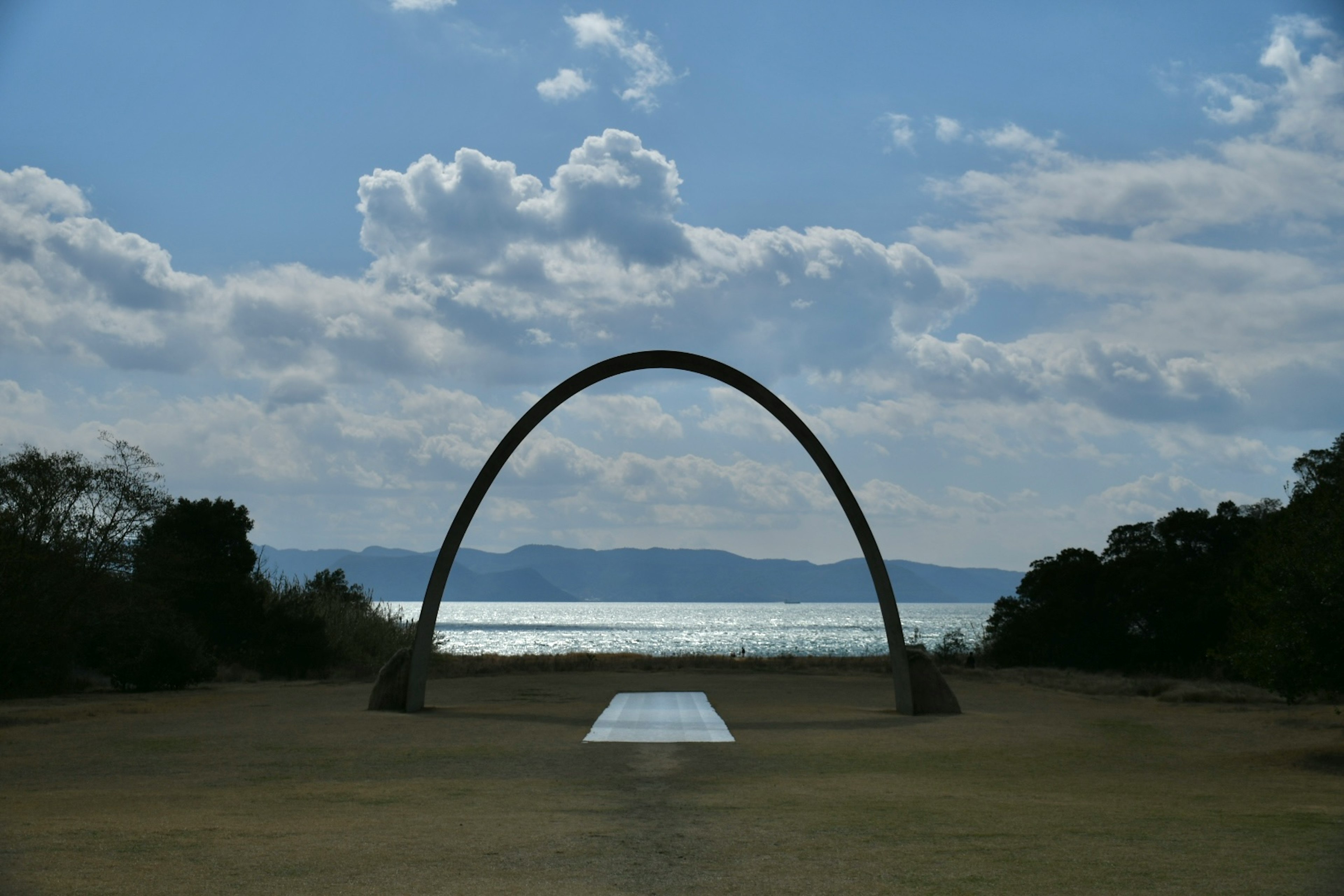 Escultura en arco con fondo oceánico y cielo azul