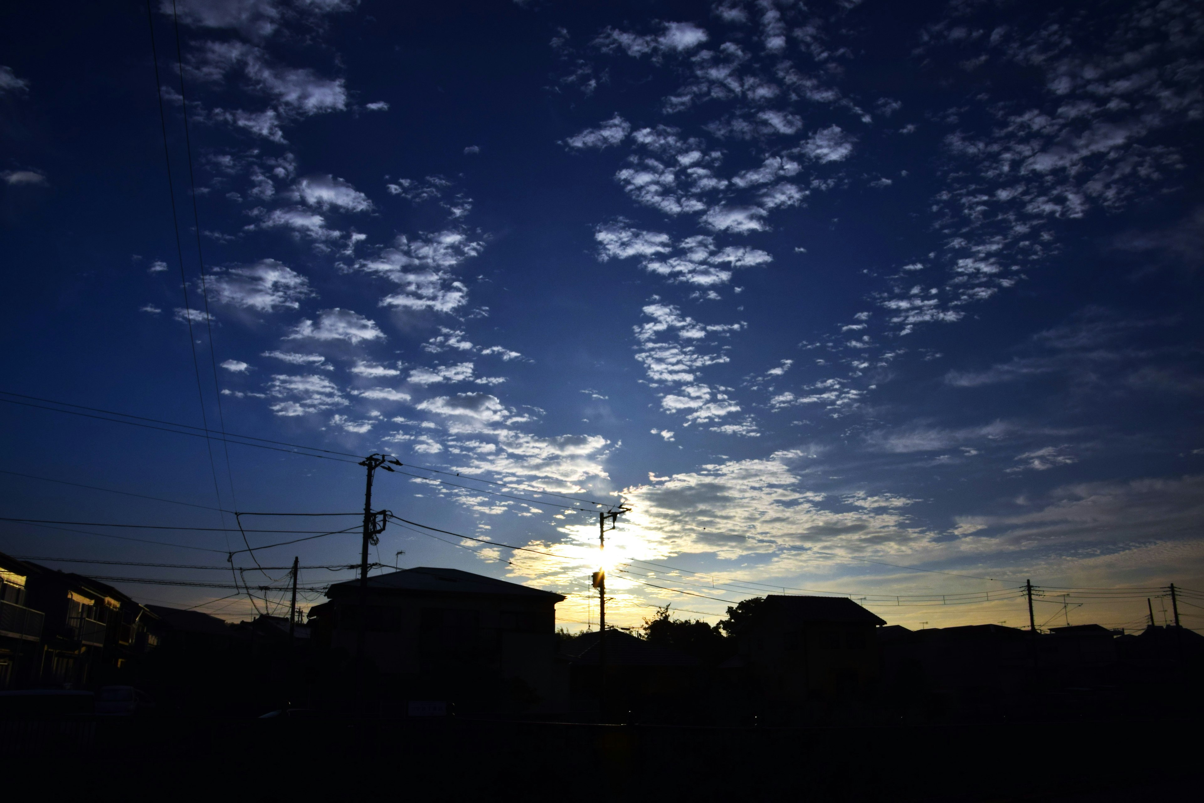 房屋輪廓在藍色黃昏天空和散布的雲朵下