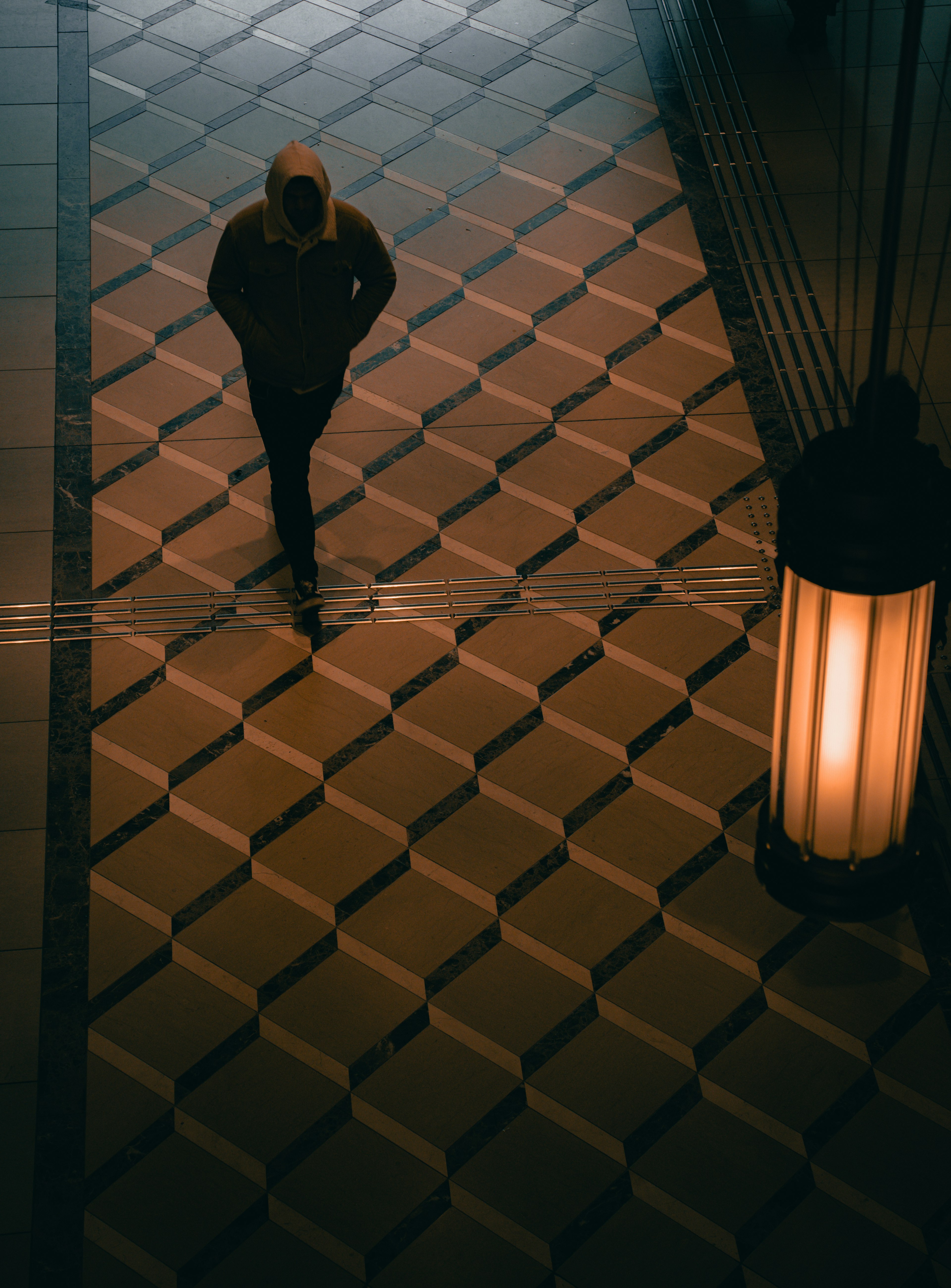 A person walking in a dimly lit area with geometric patterned flooring