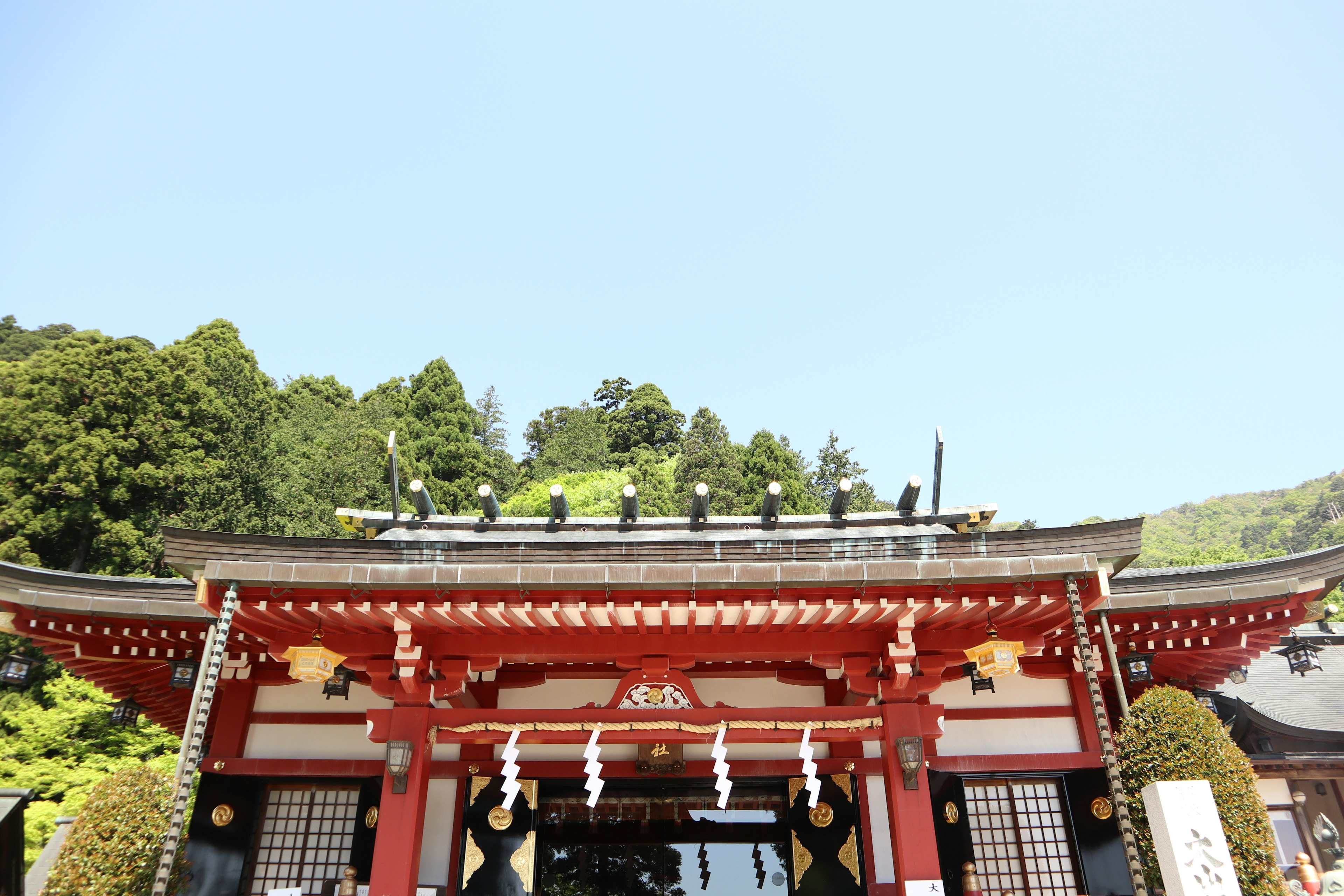 Red shrine gate with a clear blue sky background green hills in the distance