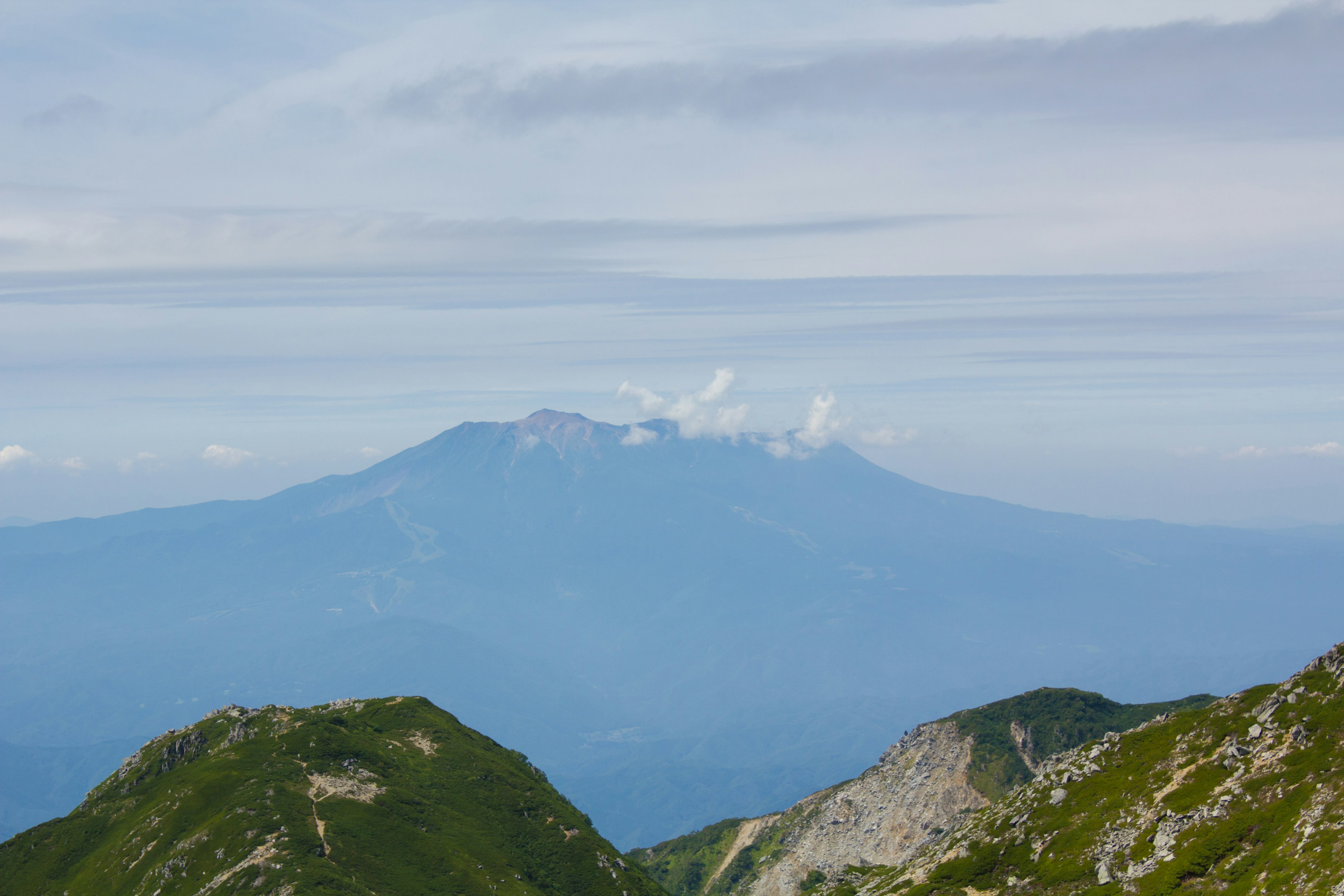 Panorama montano con cime lontane contro un cielo blu e nuvole