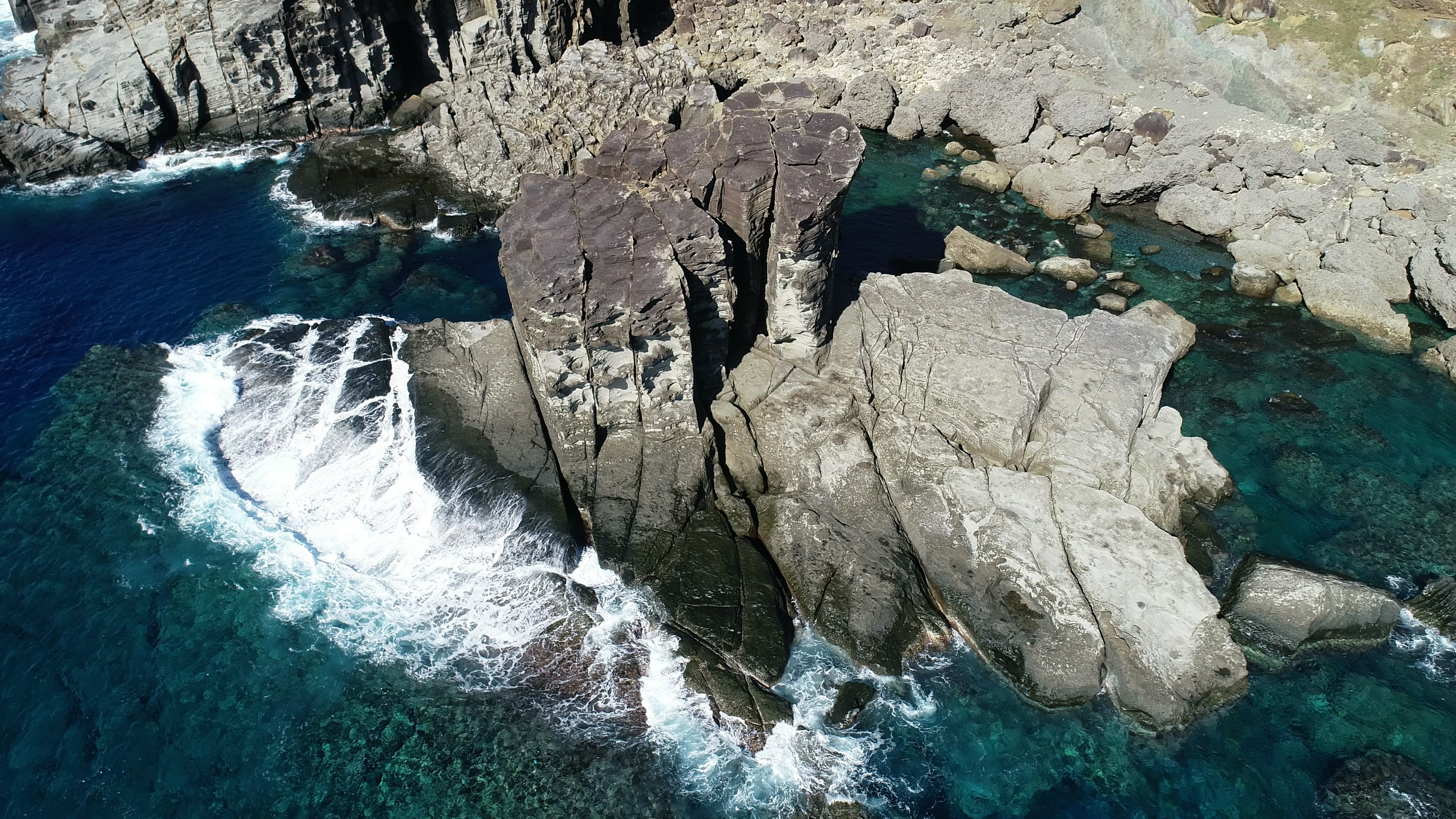 Vista aérea de una costa rocosa con agua clara y olas rompiendo