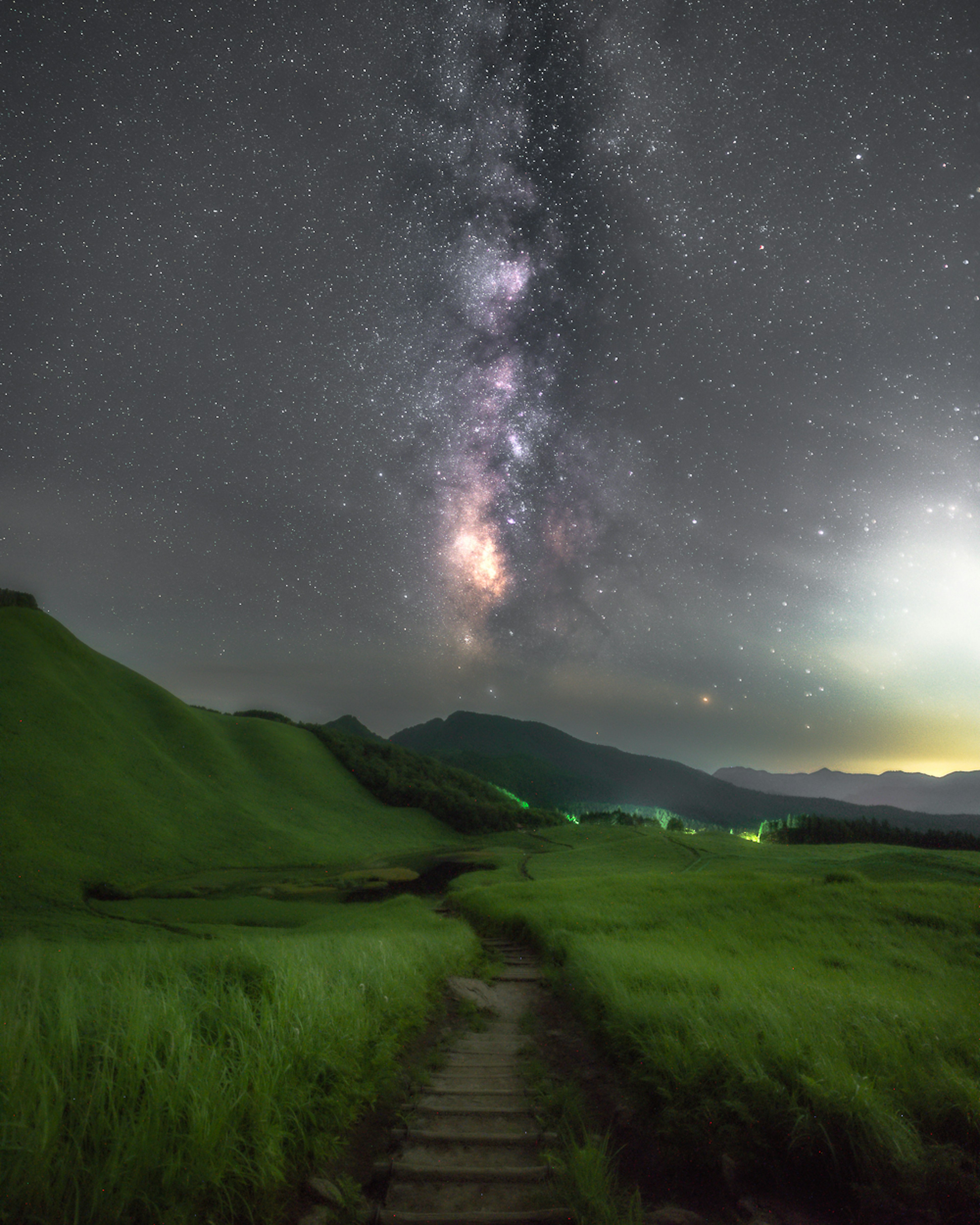 Scenic view of green hills and a path under a starry sky