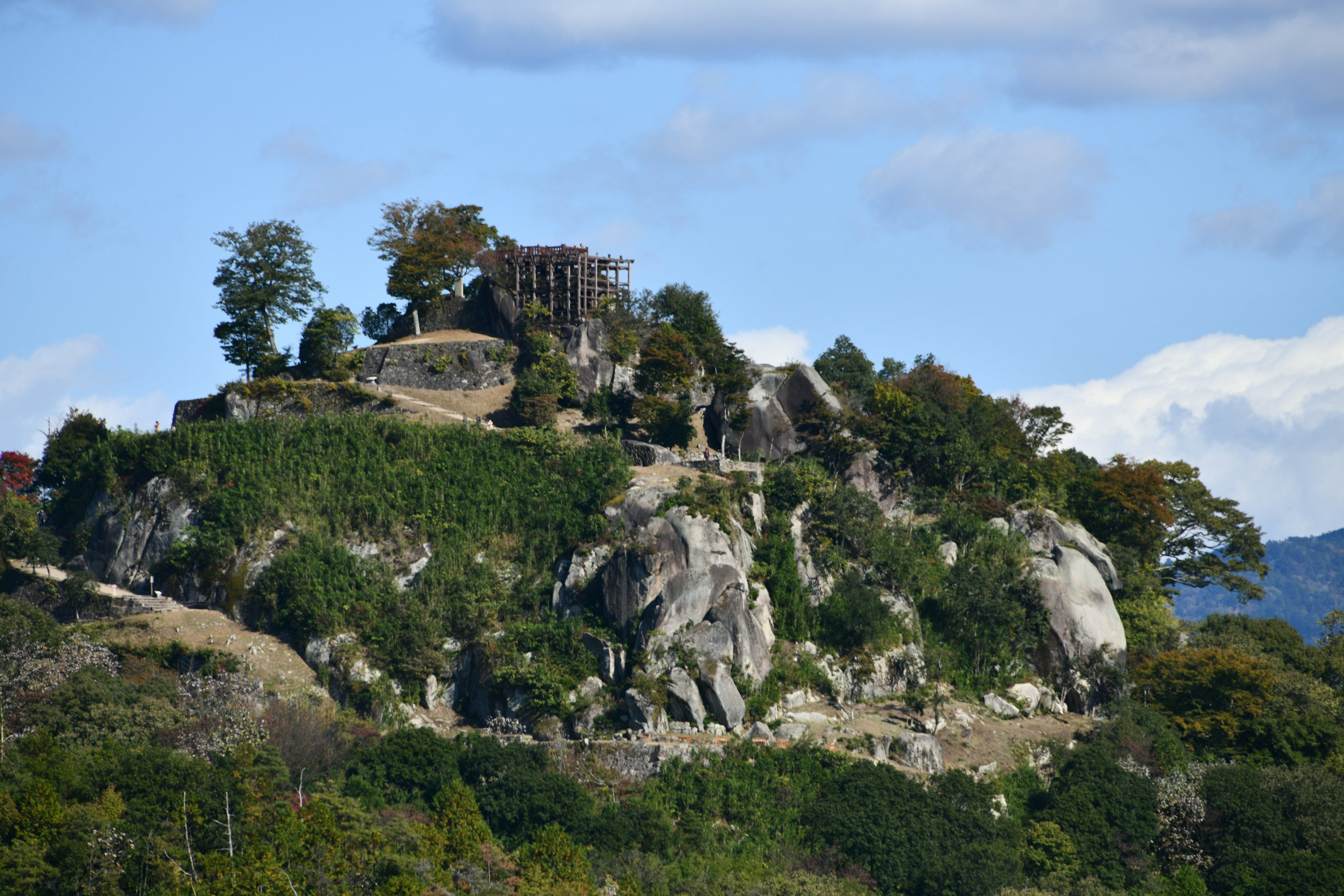 Una struttura antica su una collina rocciosa circondata da vegetazione lussureggiante