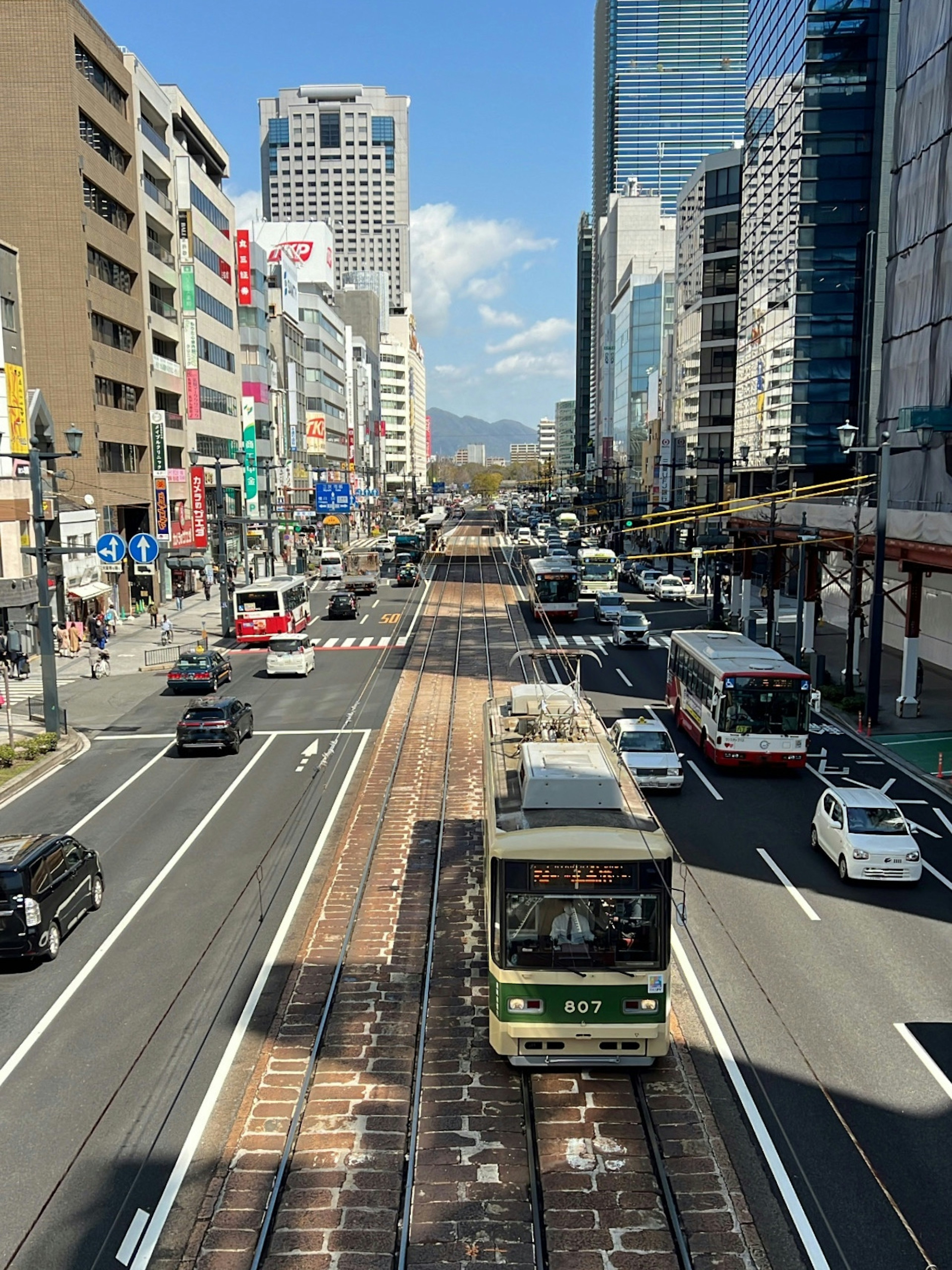 Urban scene with a tram and cars on a busy street skyscrapers in the background