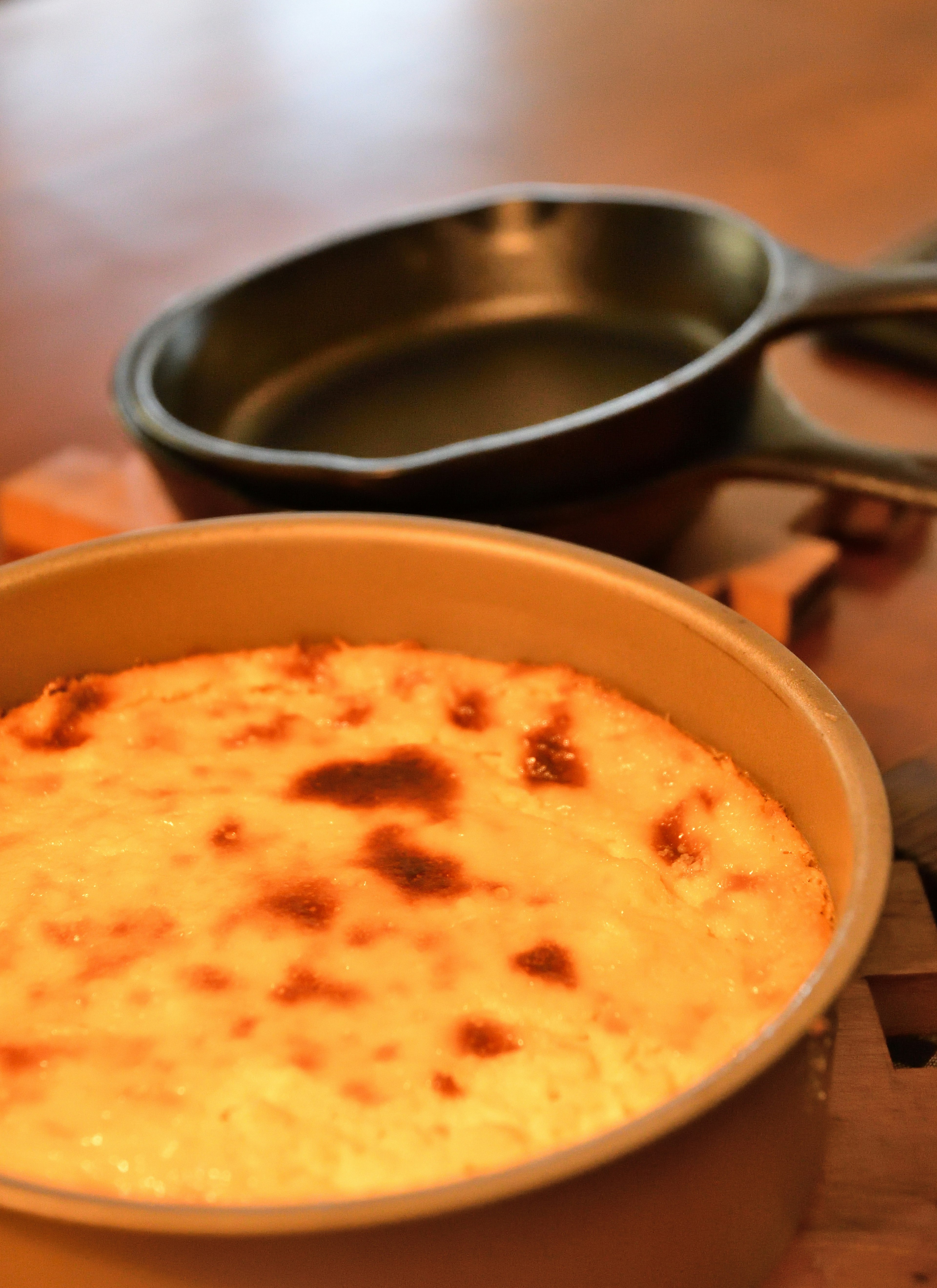 Soufflé cremoso con cima dorata accanto a una padella in ghisa