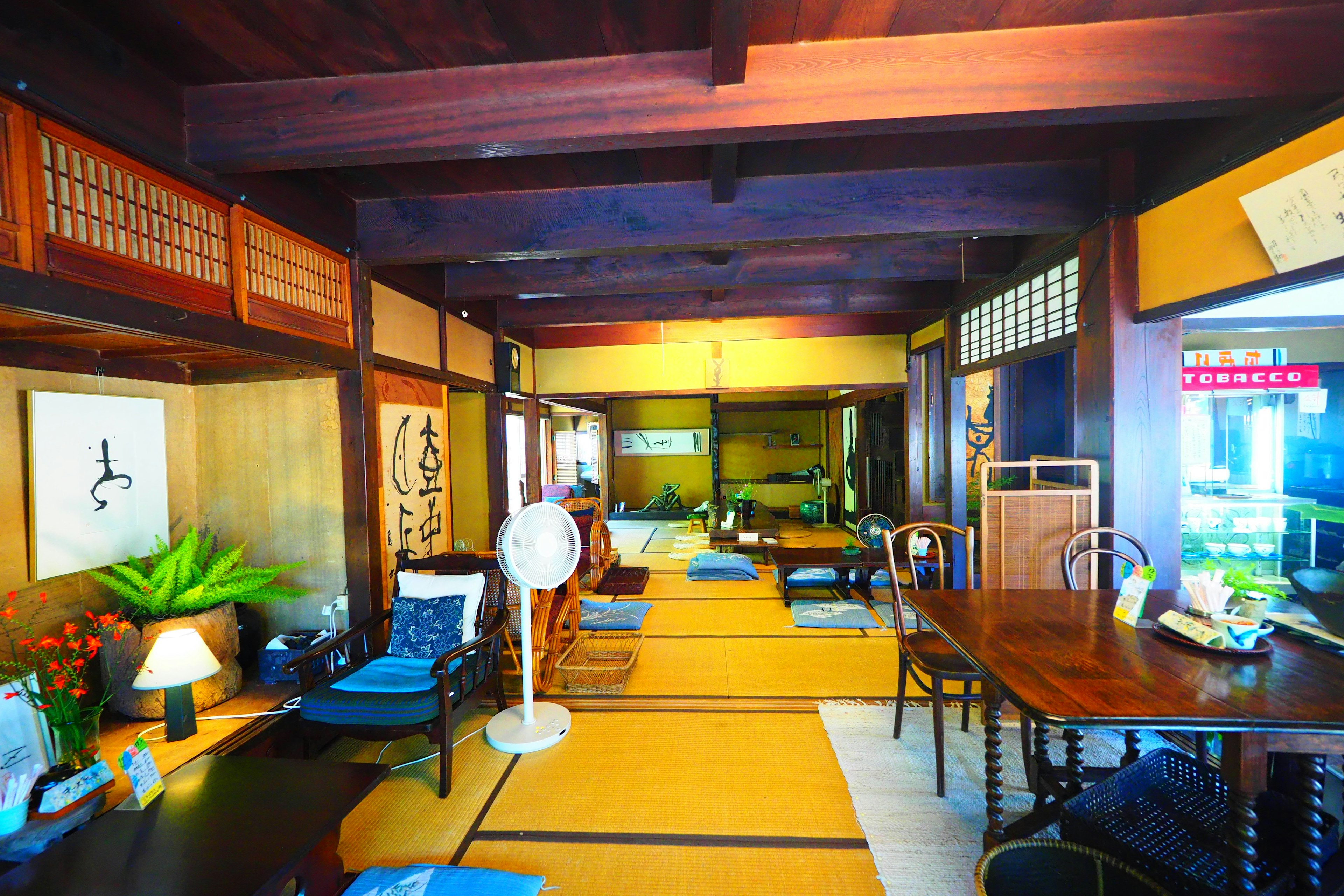 Interior of a traditional Japanese room featuring wooden beams tatami mats and a table with chairs