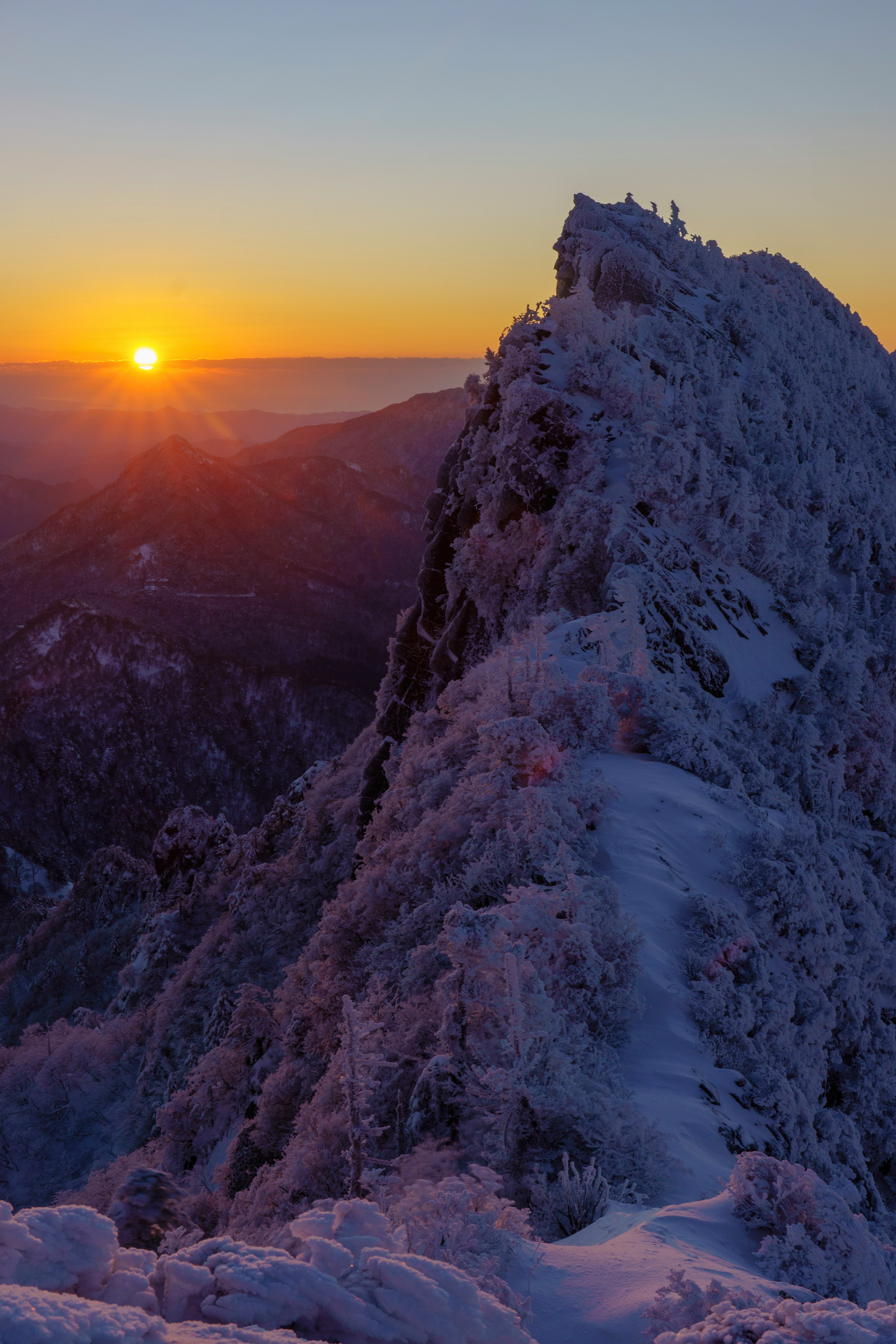 雪に覆われた山の頂上と夕日