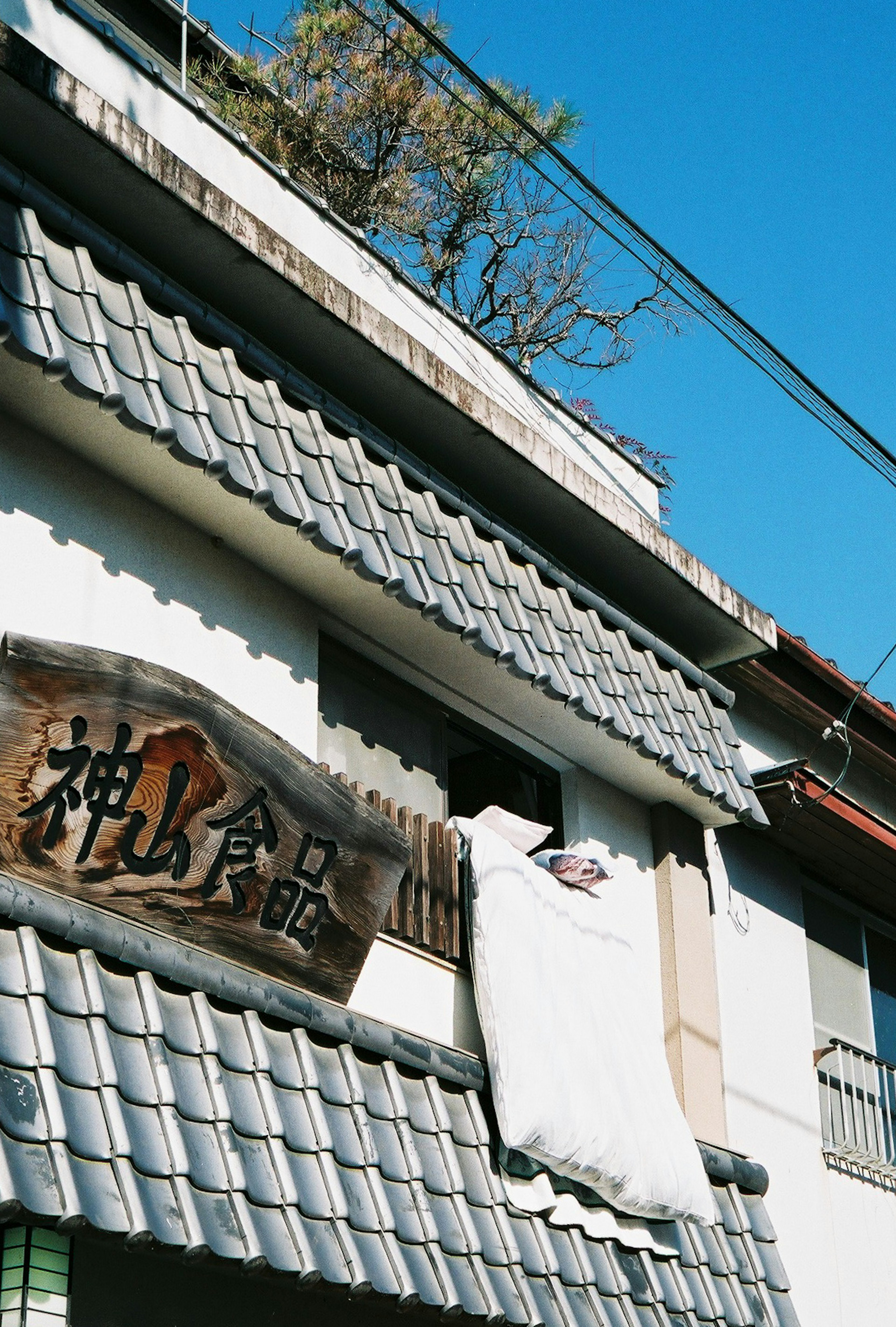 Traditionelles japanisches Gebäude mit einem Balkon, der ein weißes Tuch unter blauem Himmel zeigt