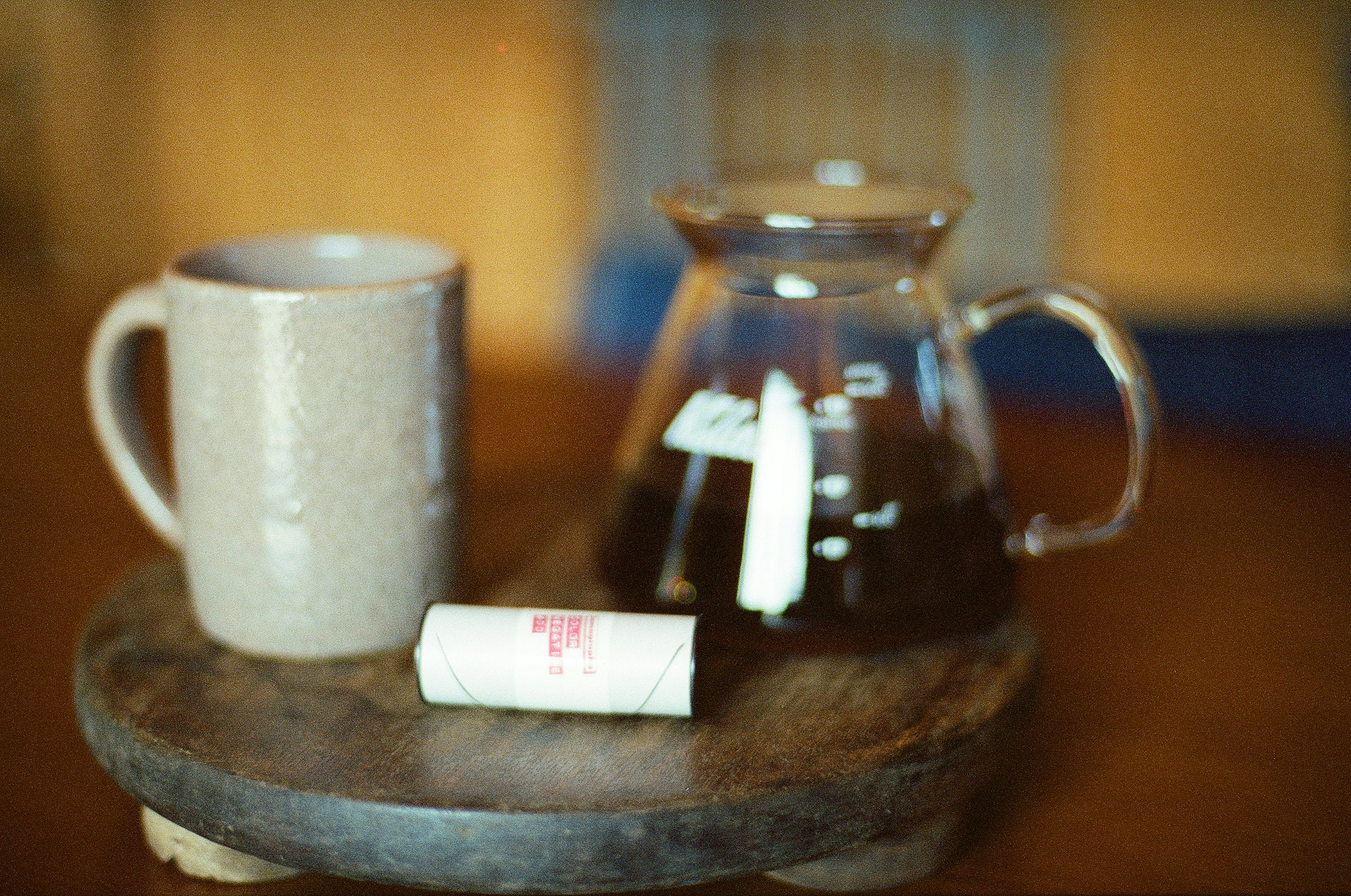 A glass coffee pot and ceramic mug placed on a wooden tray