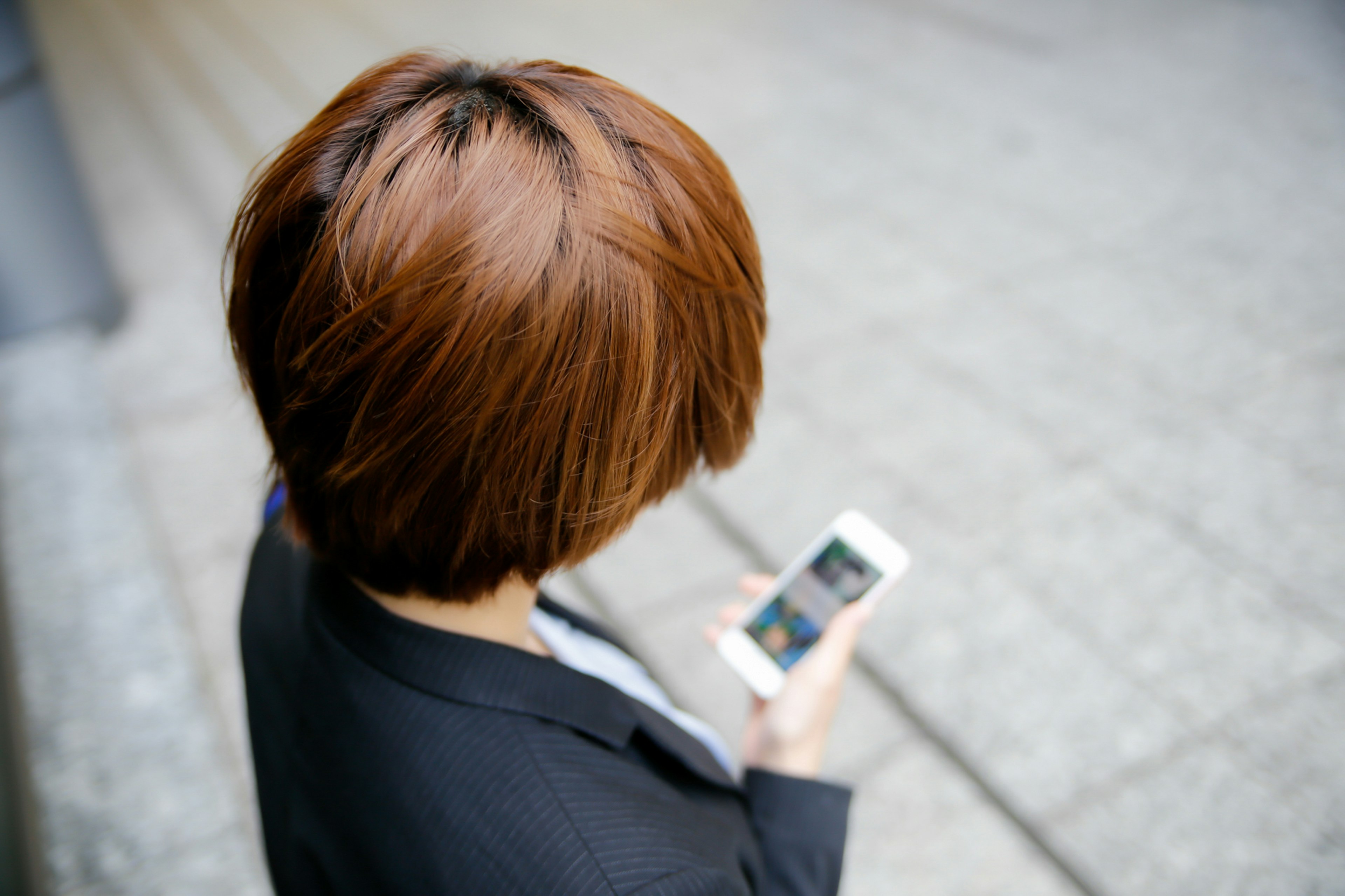 Mujer con cabello corto mirando un teléfono inteligente desde atrás