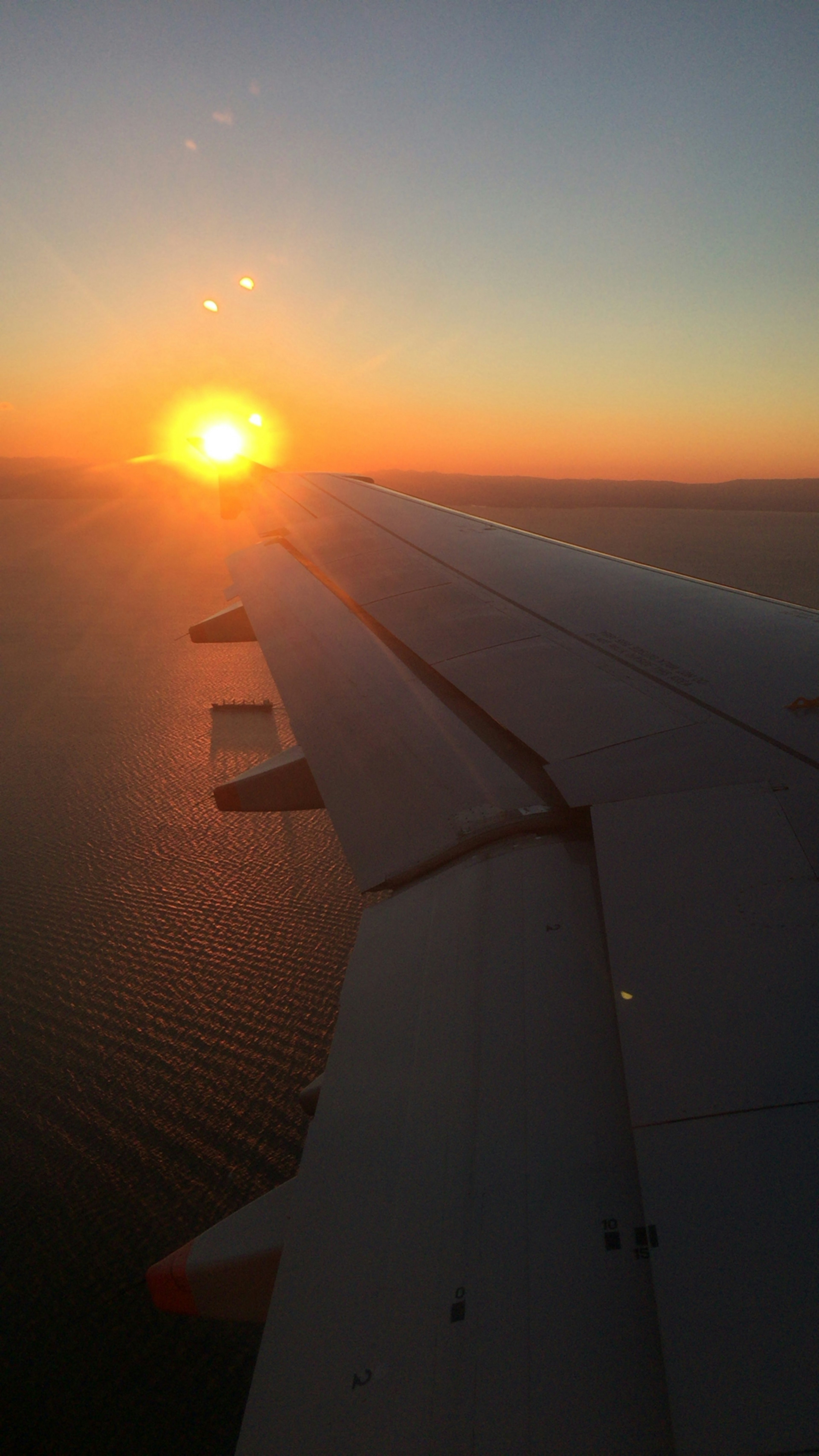 夕日が海の上に沈む美しい風景と飛行機の翼の一部