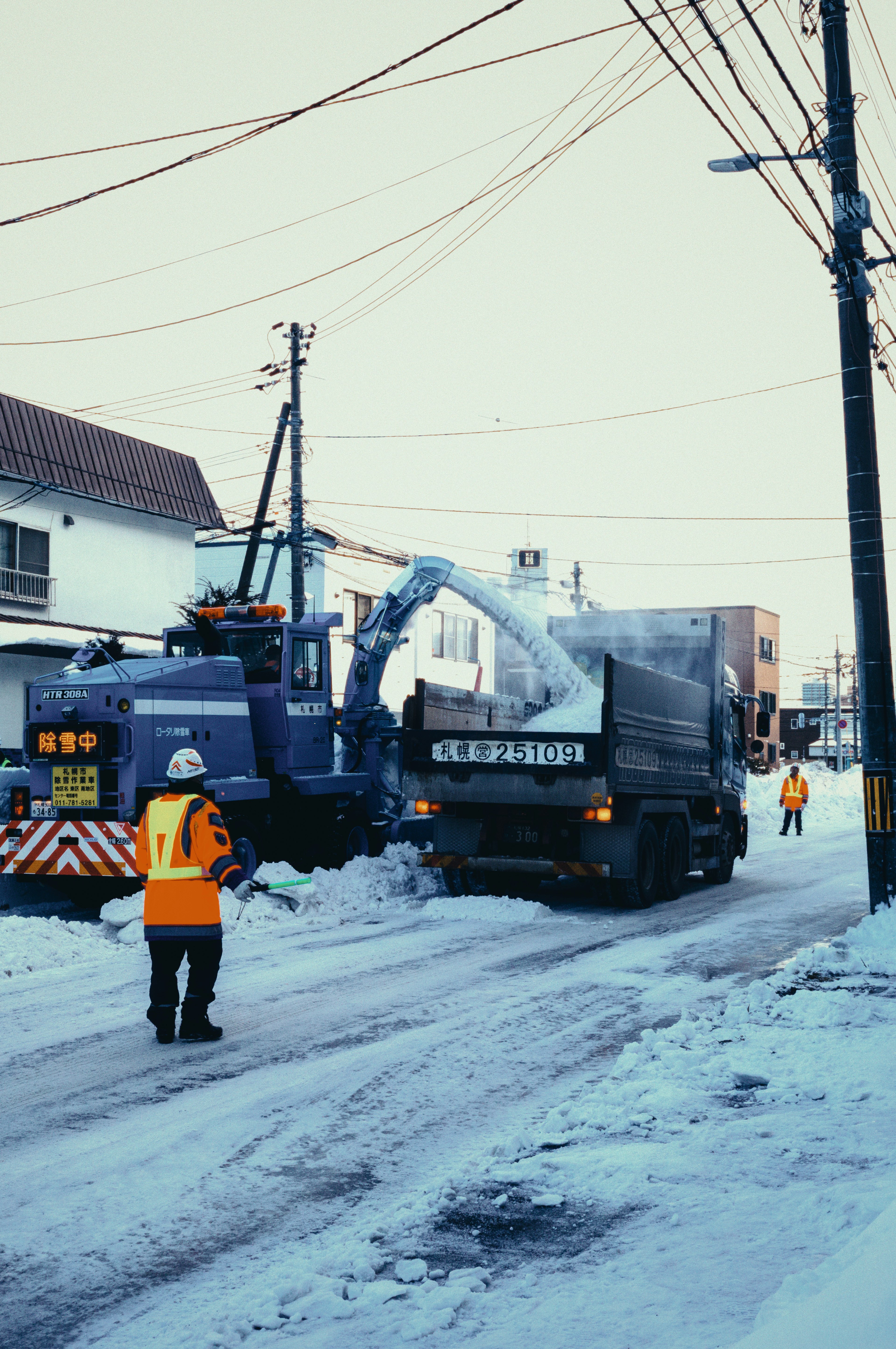 Camión de remoción de nieve y trabajadores en una calle nevada