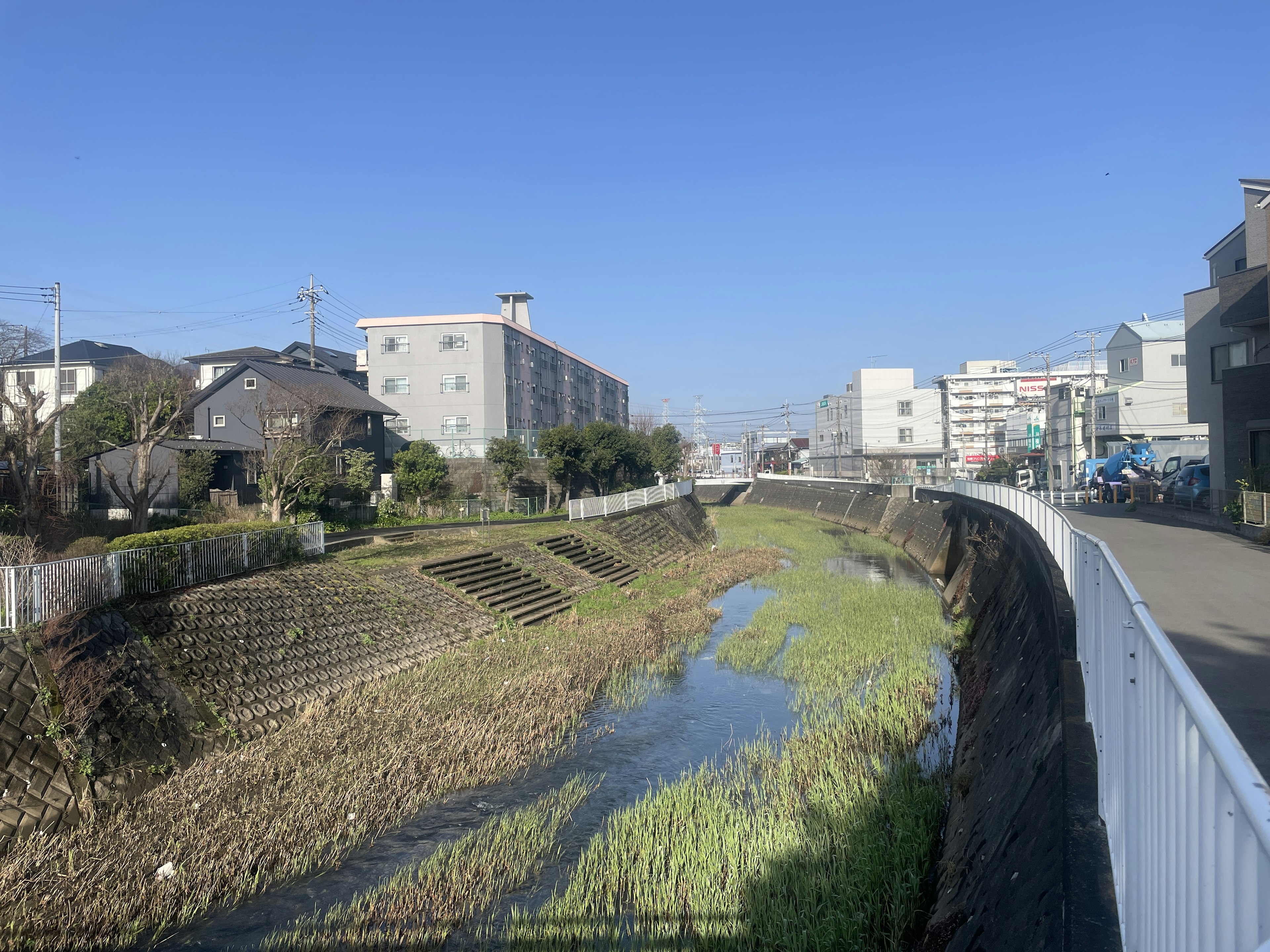 Scenic view of a calm river with surrounding buildings under a clear blue sky