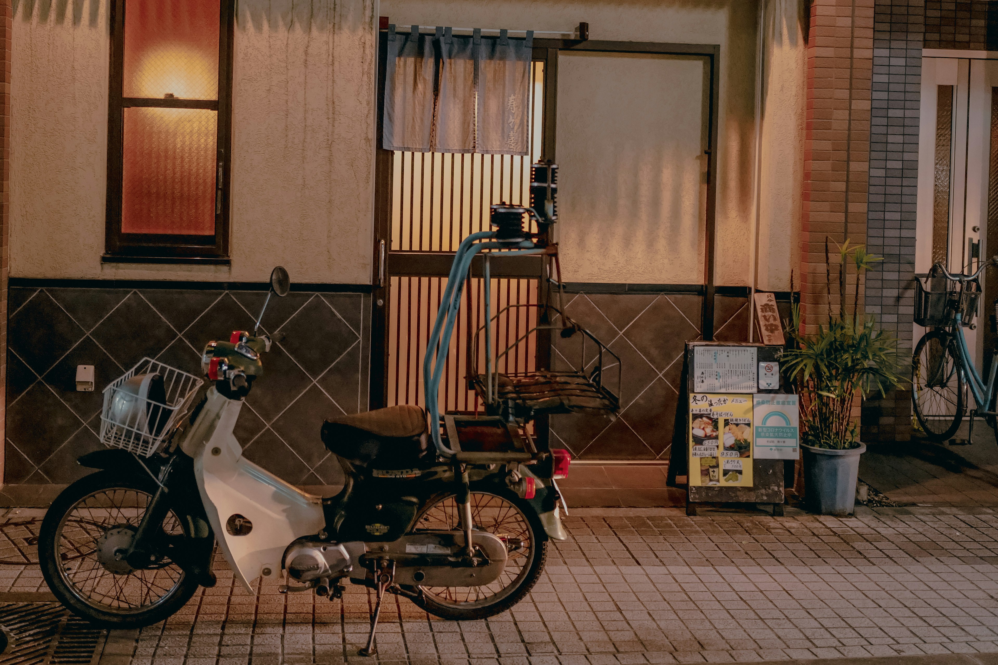 静かな夜の街角に停まっている白いバイクと和風の建物