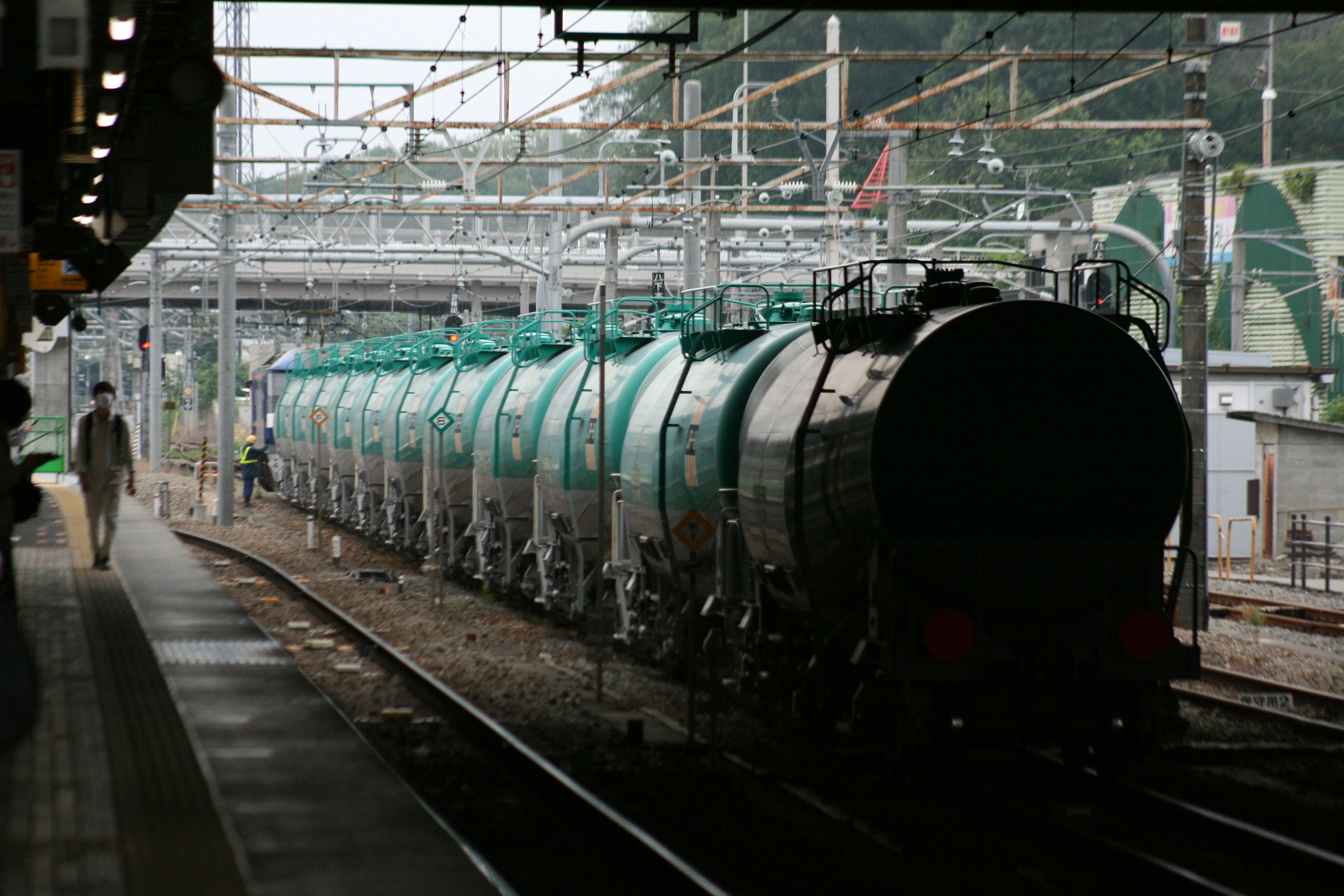 A row of green tank cars at a train station platform