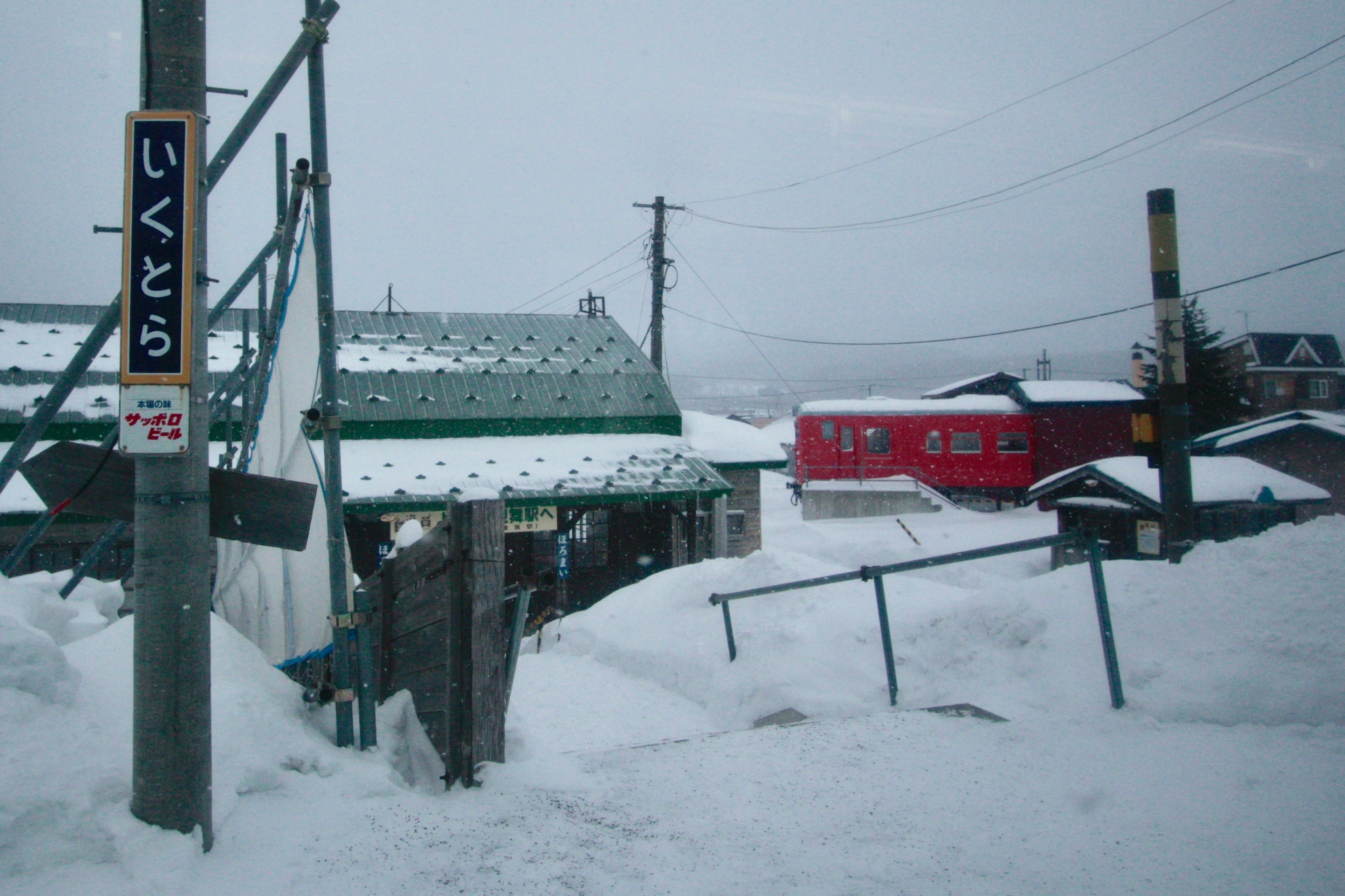 雪に覆われた道と建物の風景 赤いトラックと看板が見える