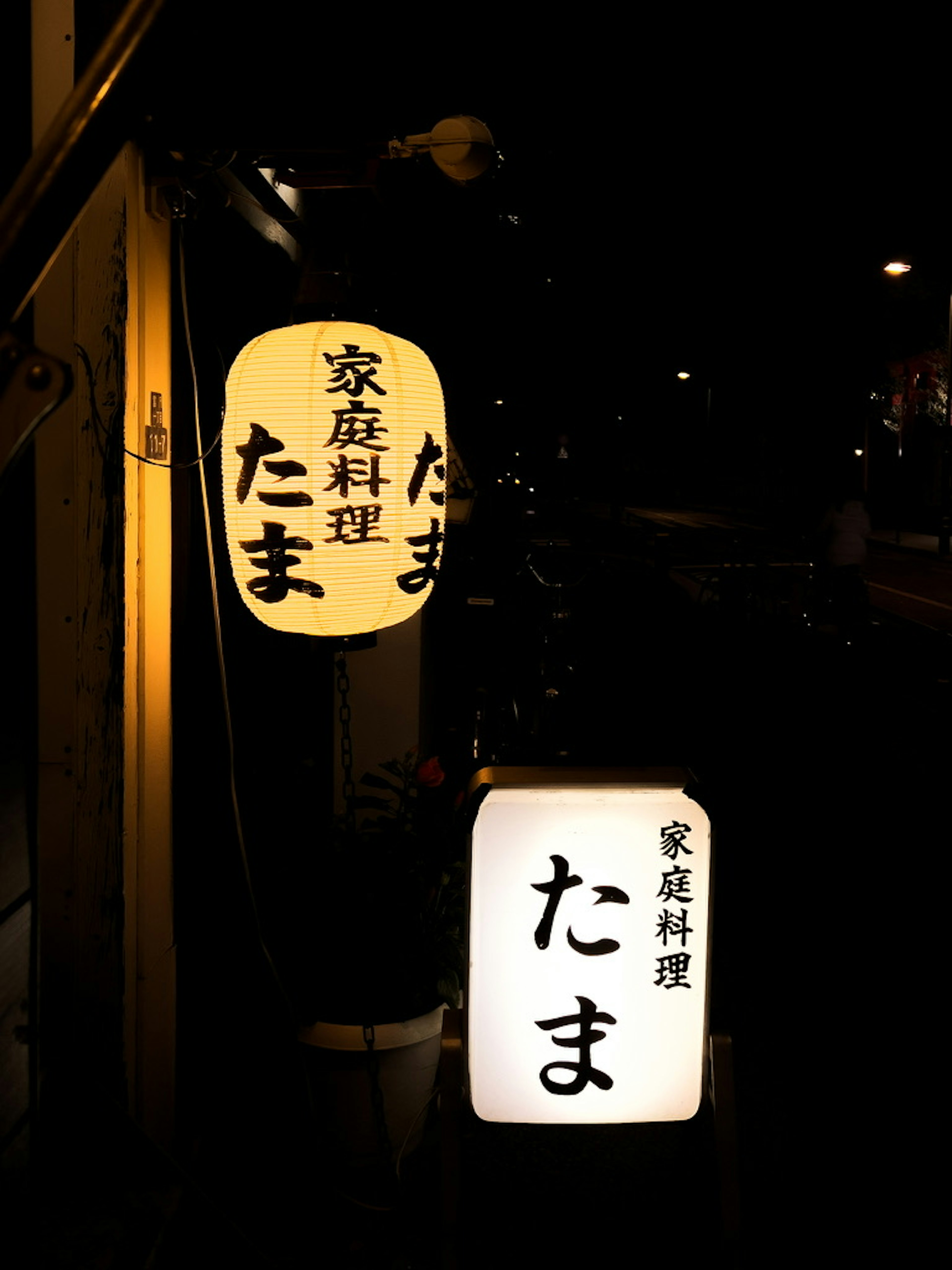 Helle Laterne und Schild von Tamate, einem Restaurant für Hausmannskost bei Nacht