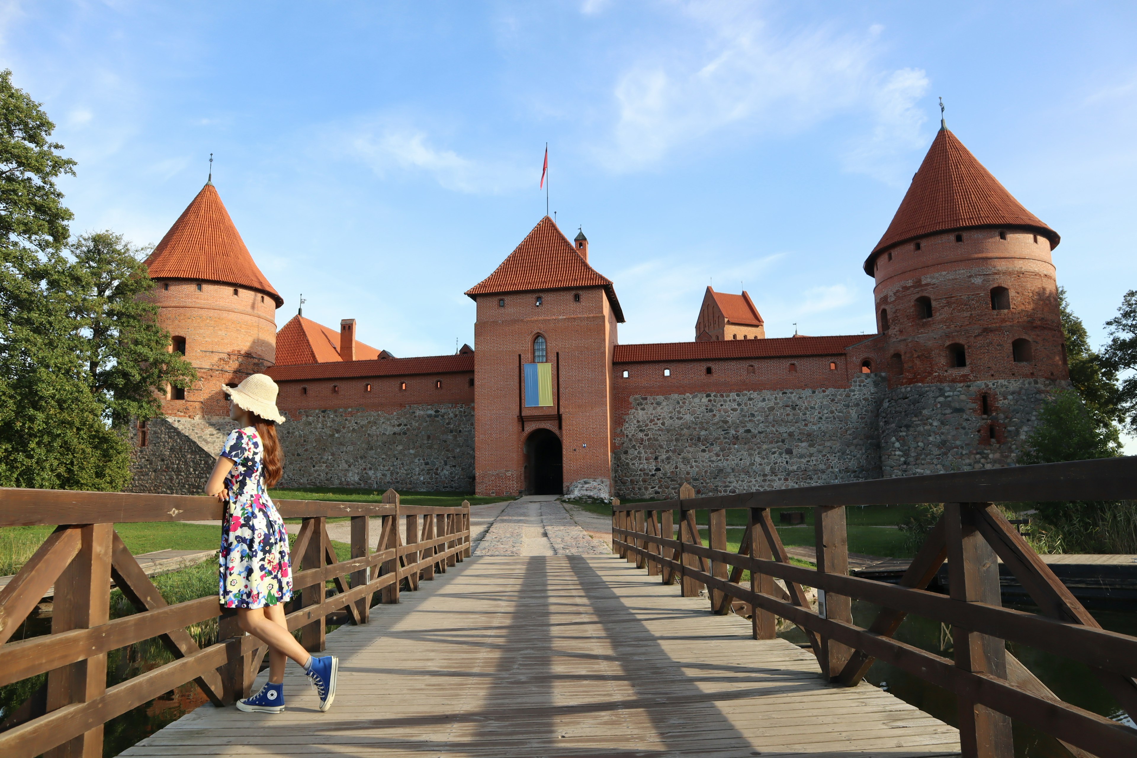 A woman walking on a wooden bridge with a castle in the background