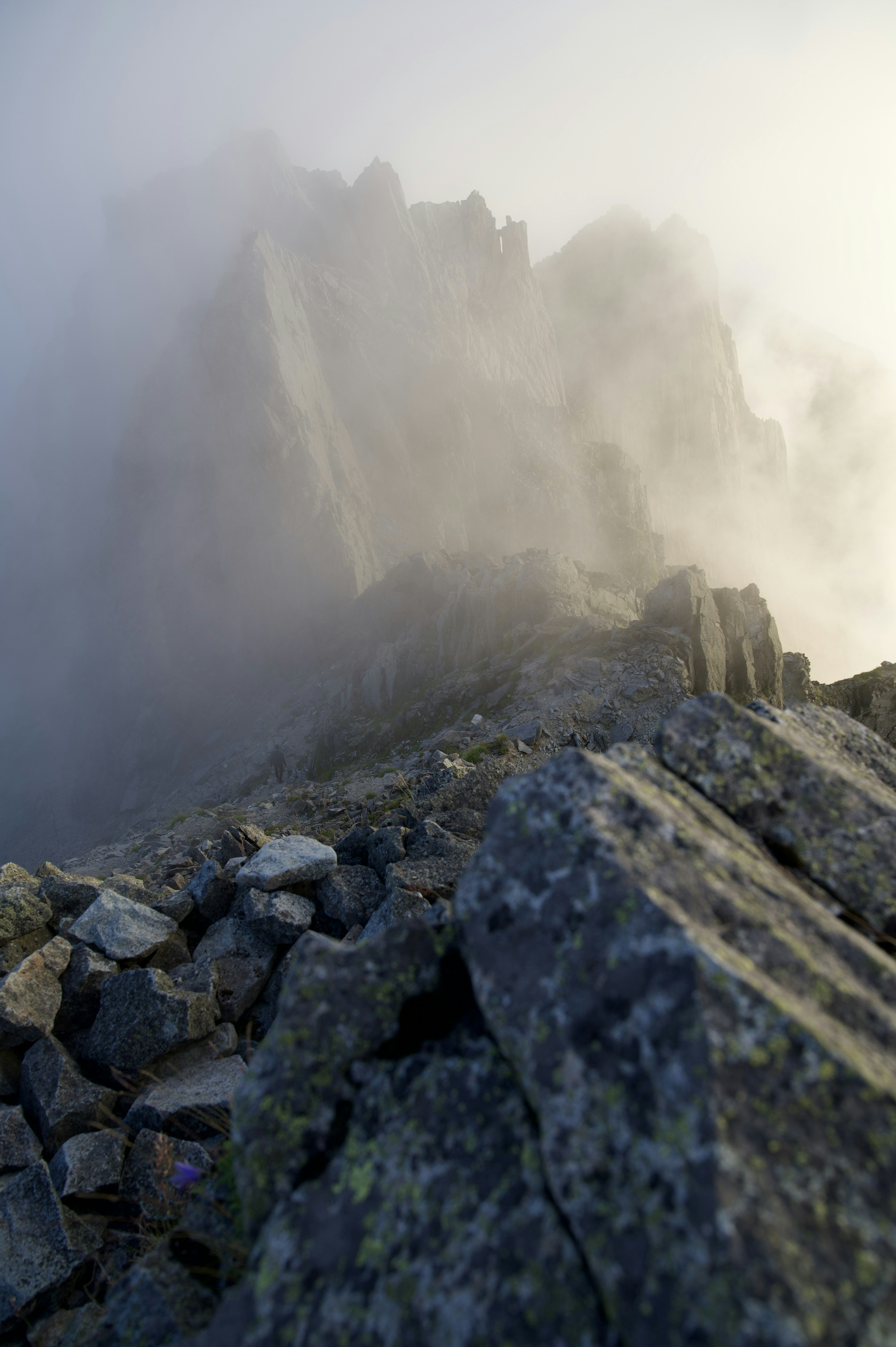 Scenic view of a mountain peak surrounded by mist with visible rocks