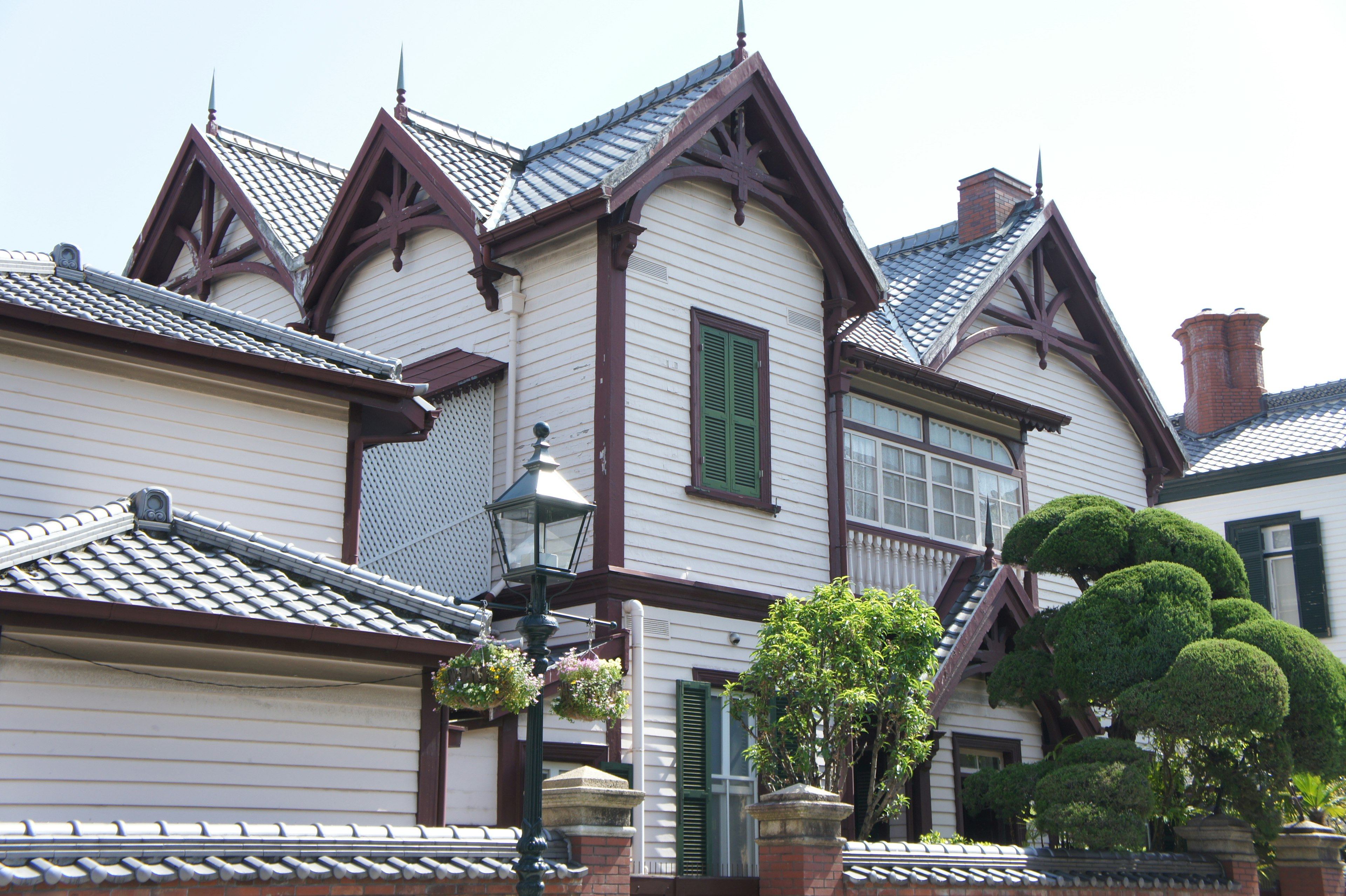 Charmante maison de style occidental avec un toit unique et une verdure luxuriante