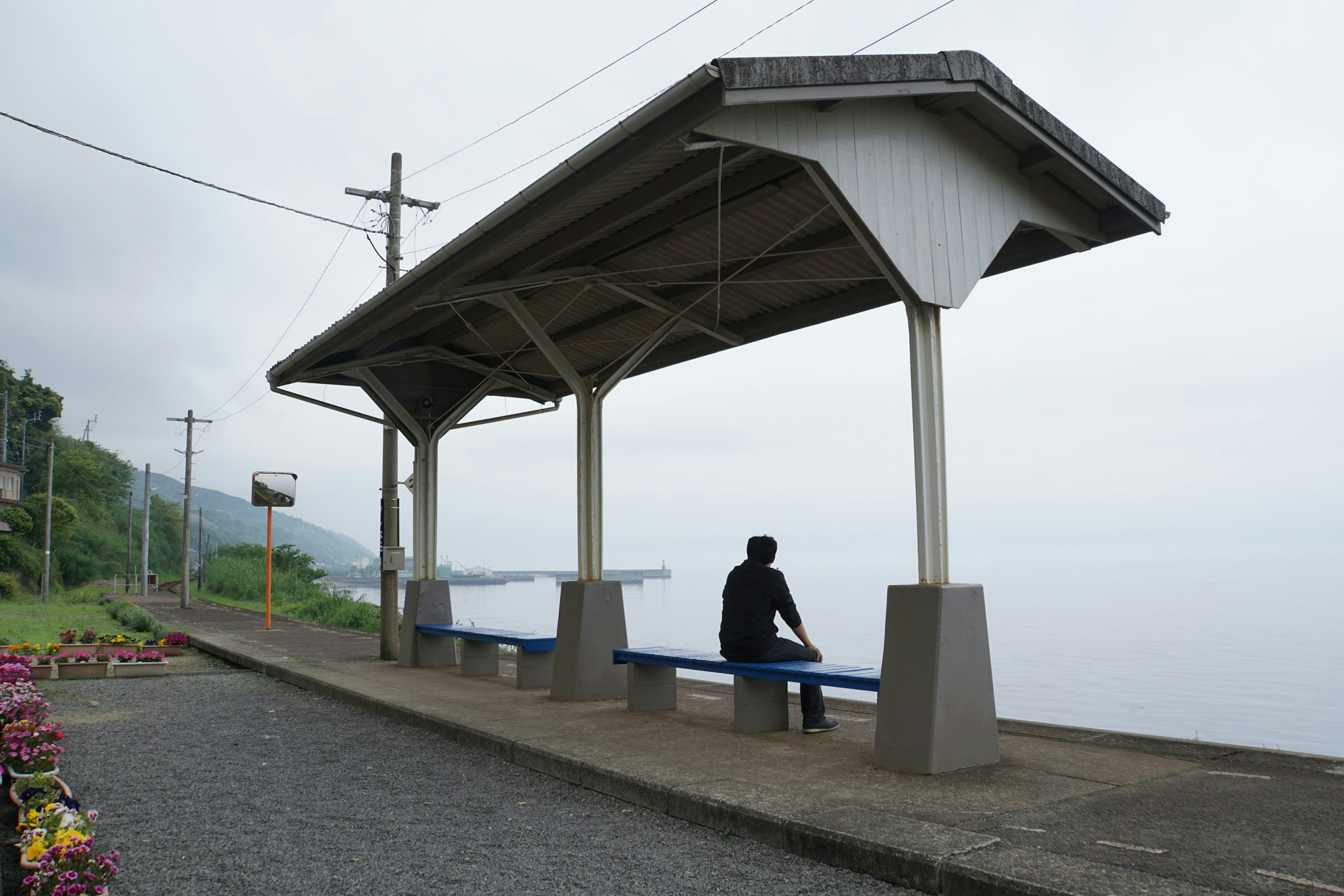 海の見える静かなバス停で座っている男性